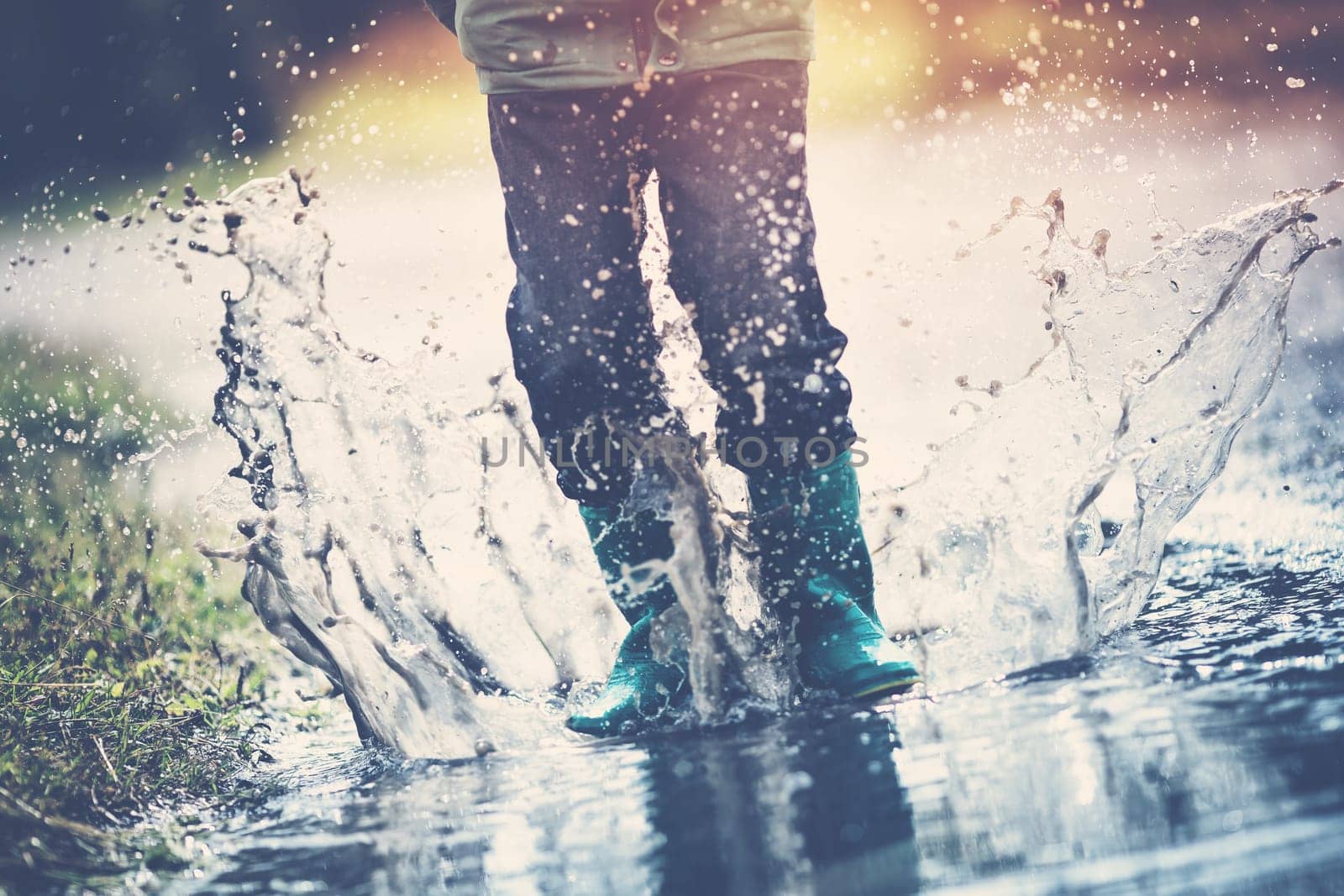Child walking in wellies in puddle on rainy weather. Boy under rain in summer