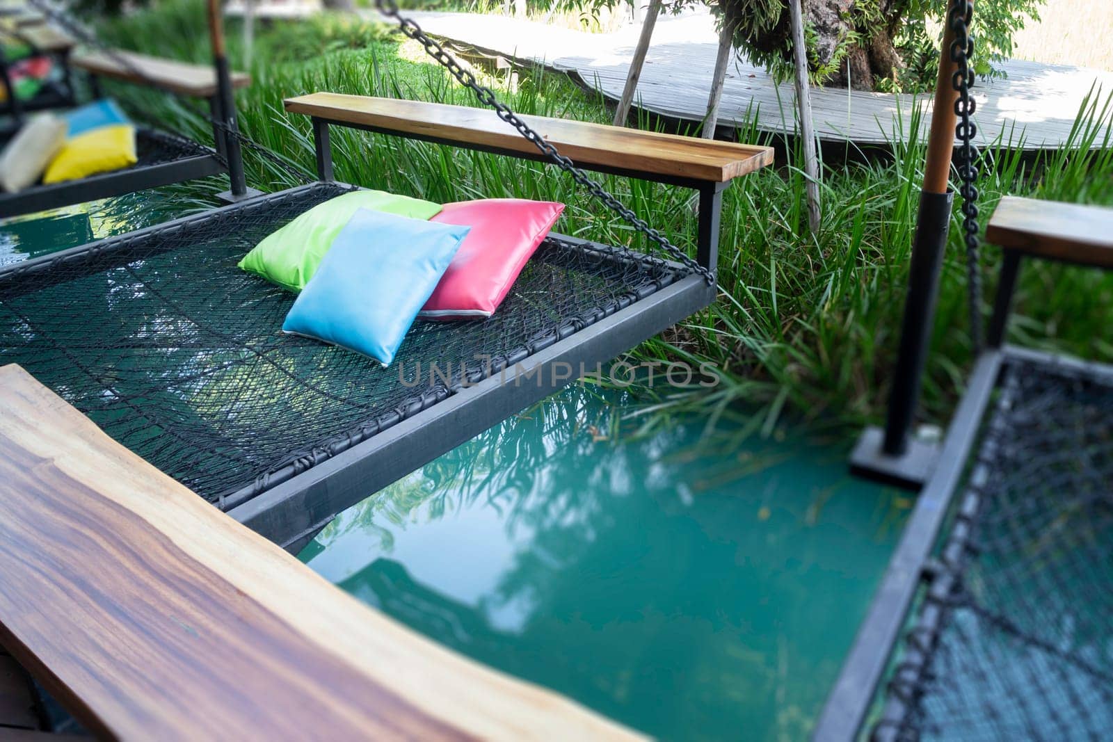 Colorful pillows on net seat among nature, stock photo