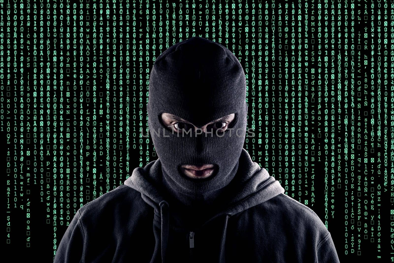 Masked cyber terrorist with black balaclava and hoodie in the dark