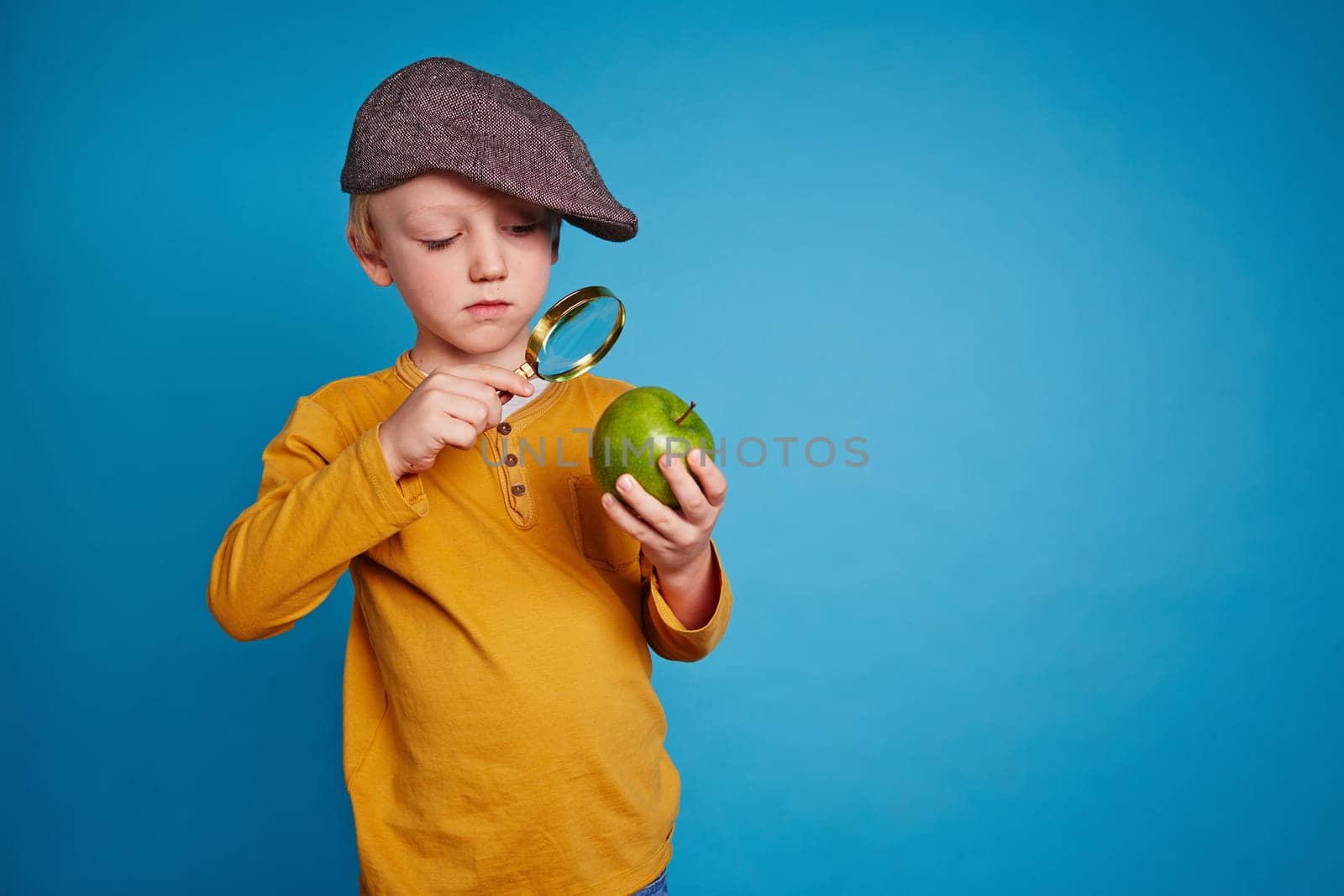 Little boy watching an apple with magnifying glass
