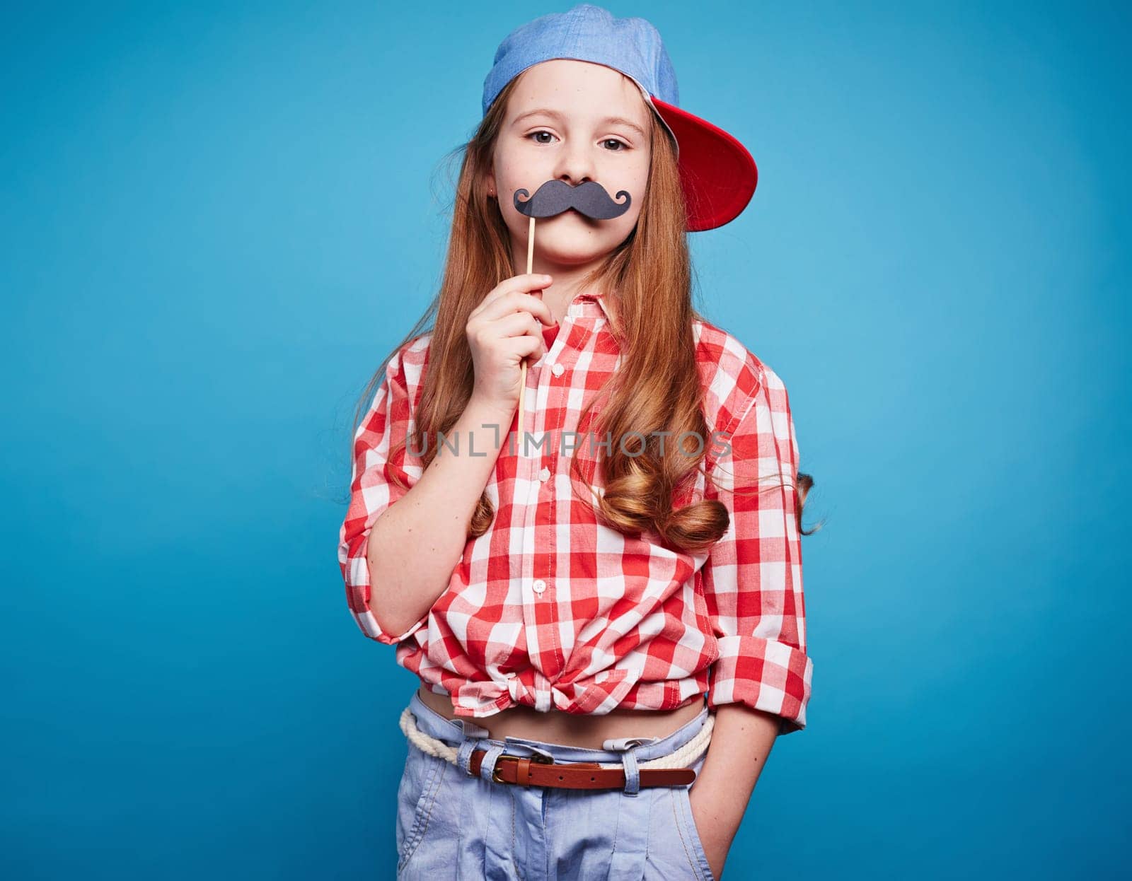 Charming girl holding moustache on a stick, like she is man