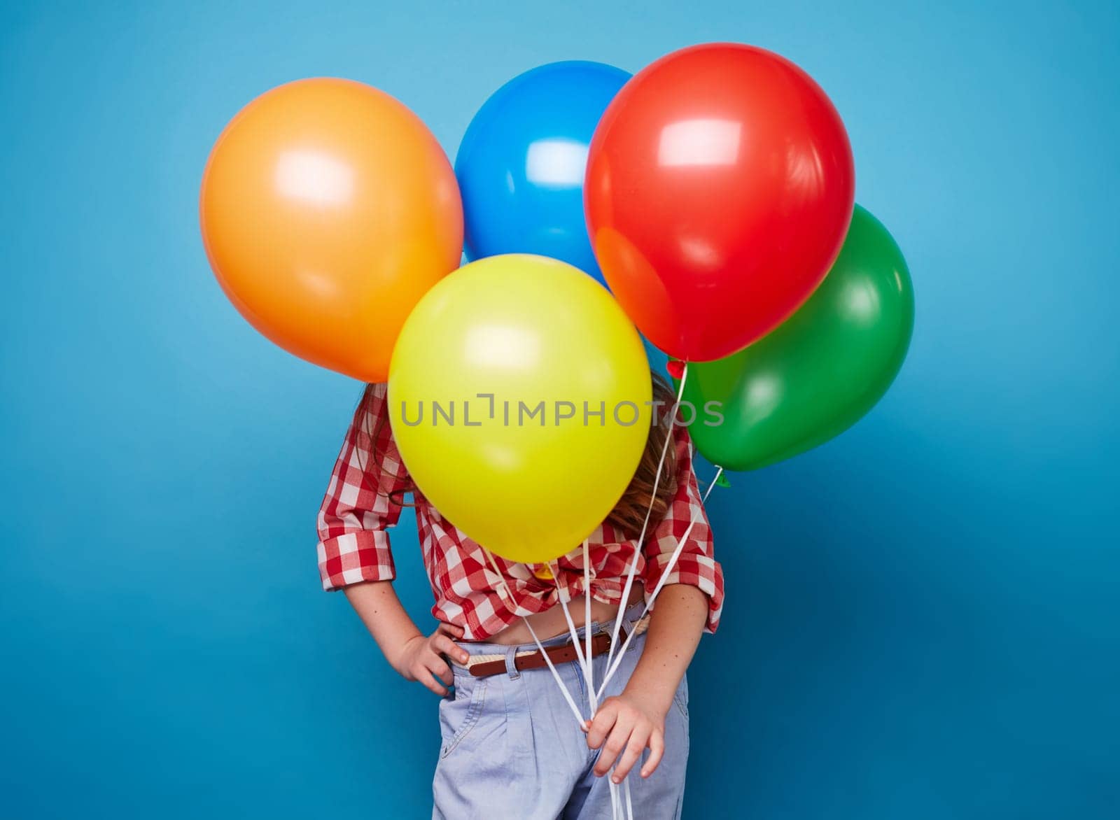 Little girl hiding behind bunch of colorful balloons