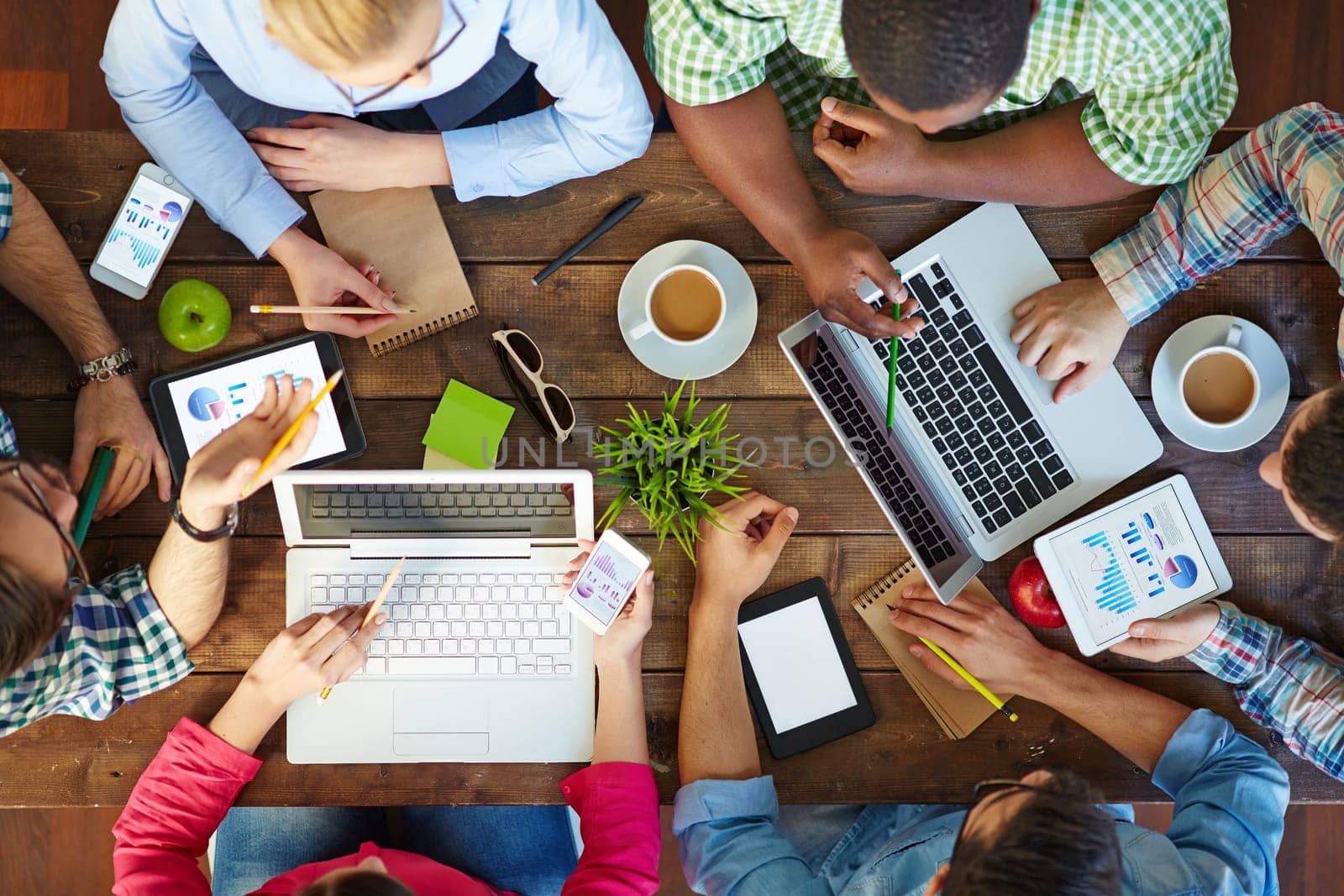 High angle view of people communicating at table with their devices