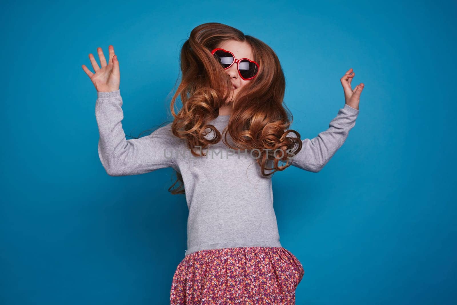 Girl in red heart-shaped glasses jumping