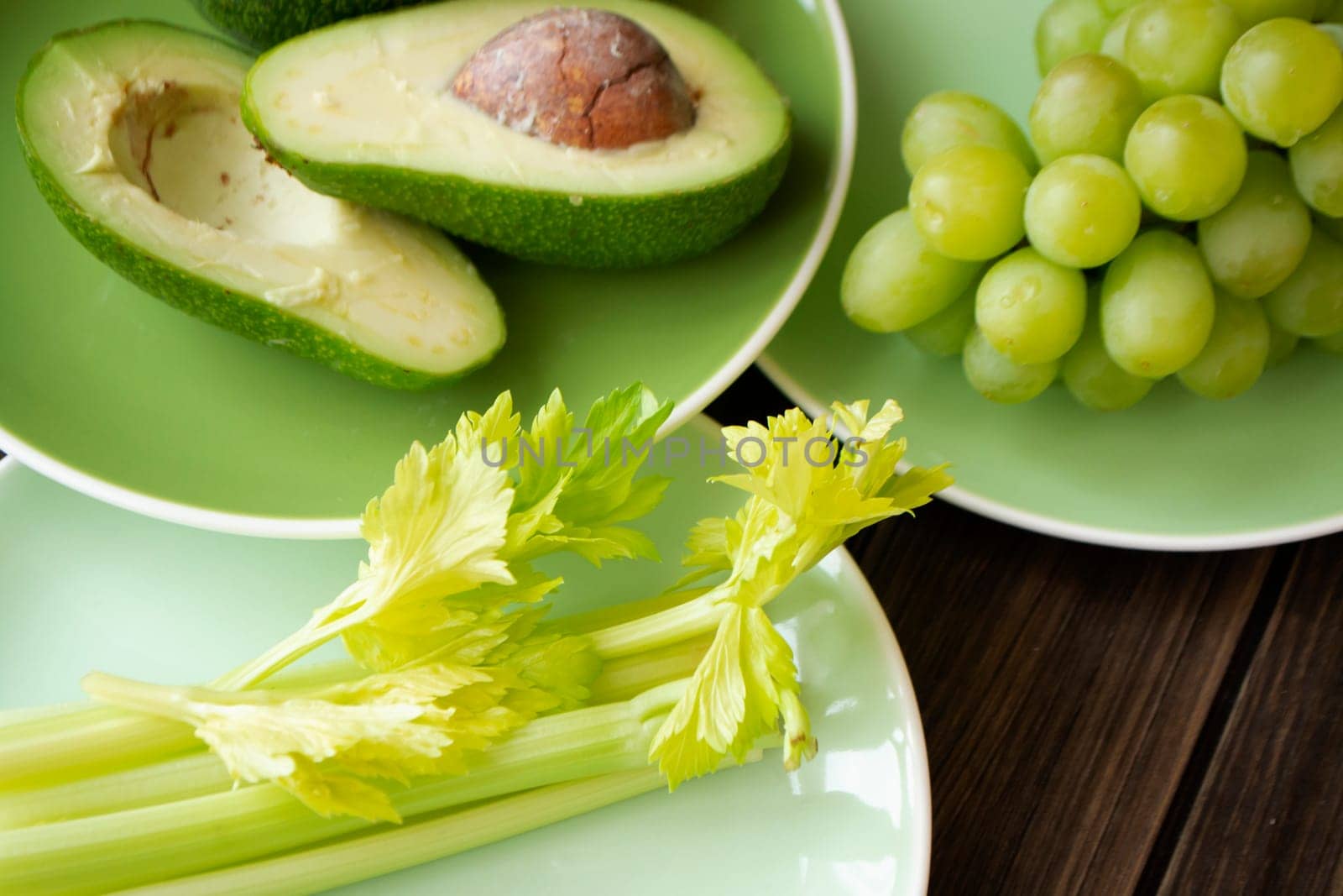 Assorted fresh green fruits and vegetables on green plates. The concept of healthy eating. Close up