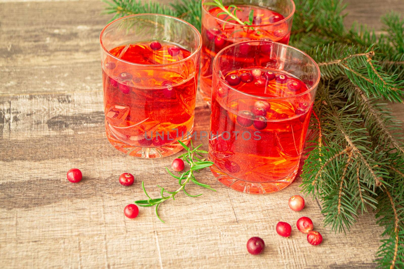 Christmas glasses of red hot mulled wine ore compote of cowberries with spices and cowberries surrounded by fir branches