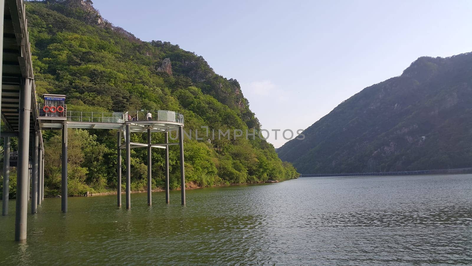 View of beautiful scene of river water and green trees on large hills on a sunny day with blue sky in background. A lovely landscape with breathtaking view over the horizon .