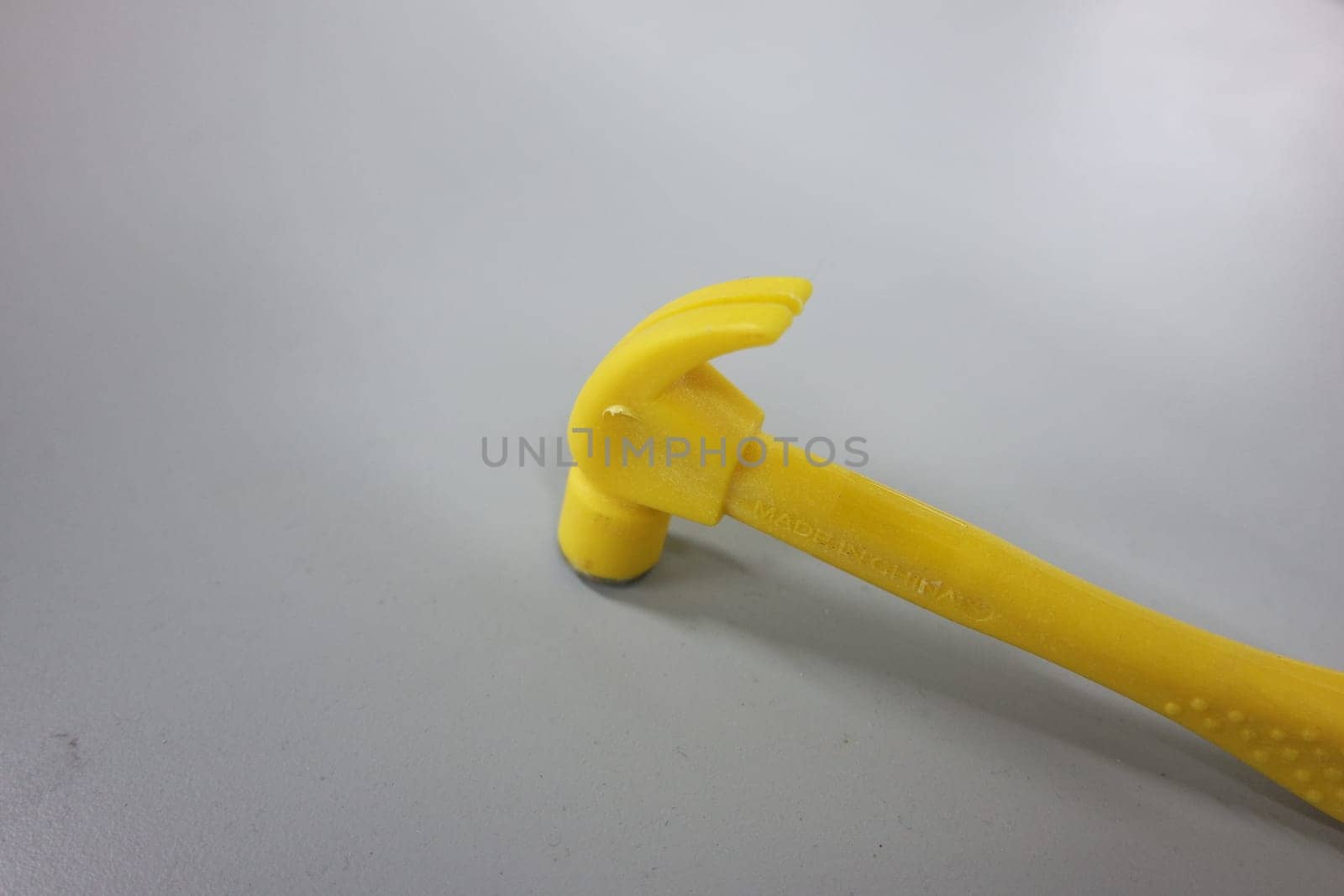 Selective focused, closeup view of toy hammer made from plastic placed on metal background