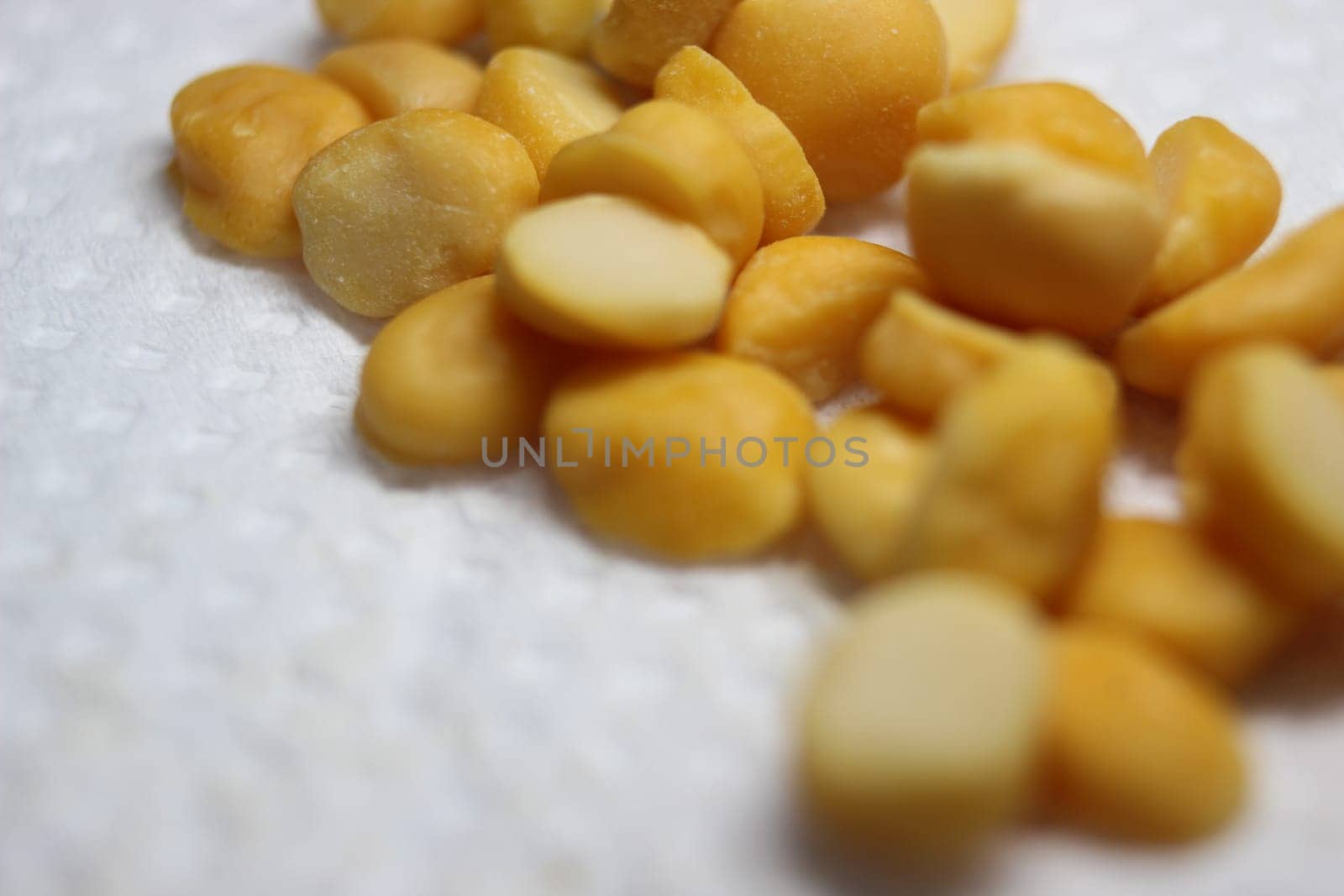 Yellow chickpea lentils seeds macro closeup view. Chana daal or yellow split peas on white blurred background