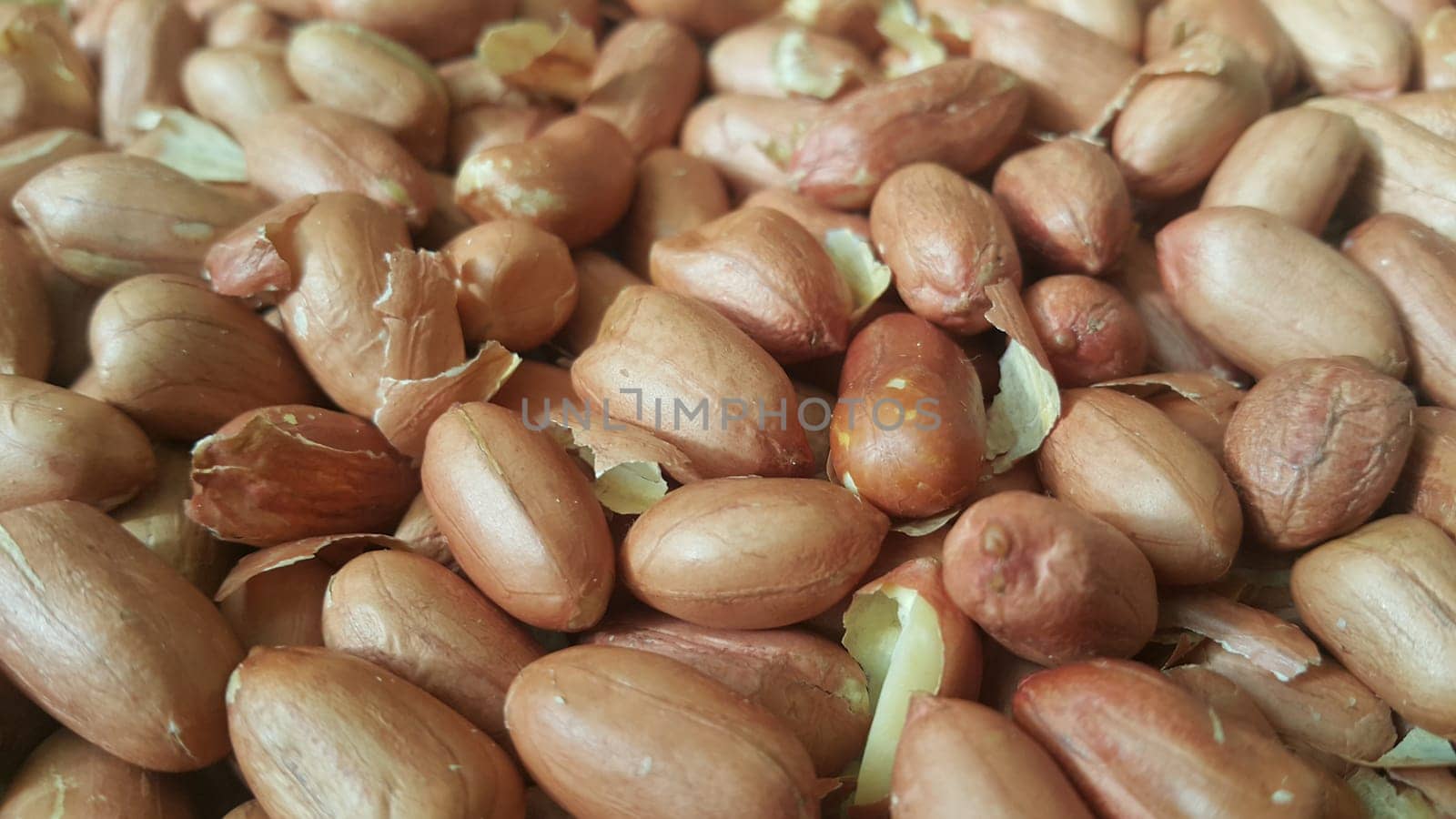 Closeup view of mixed, dried, roasted  peeled and unpeeled peanuts. A fruit for background text