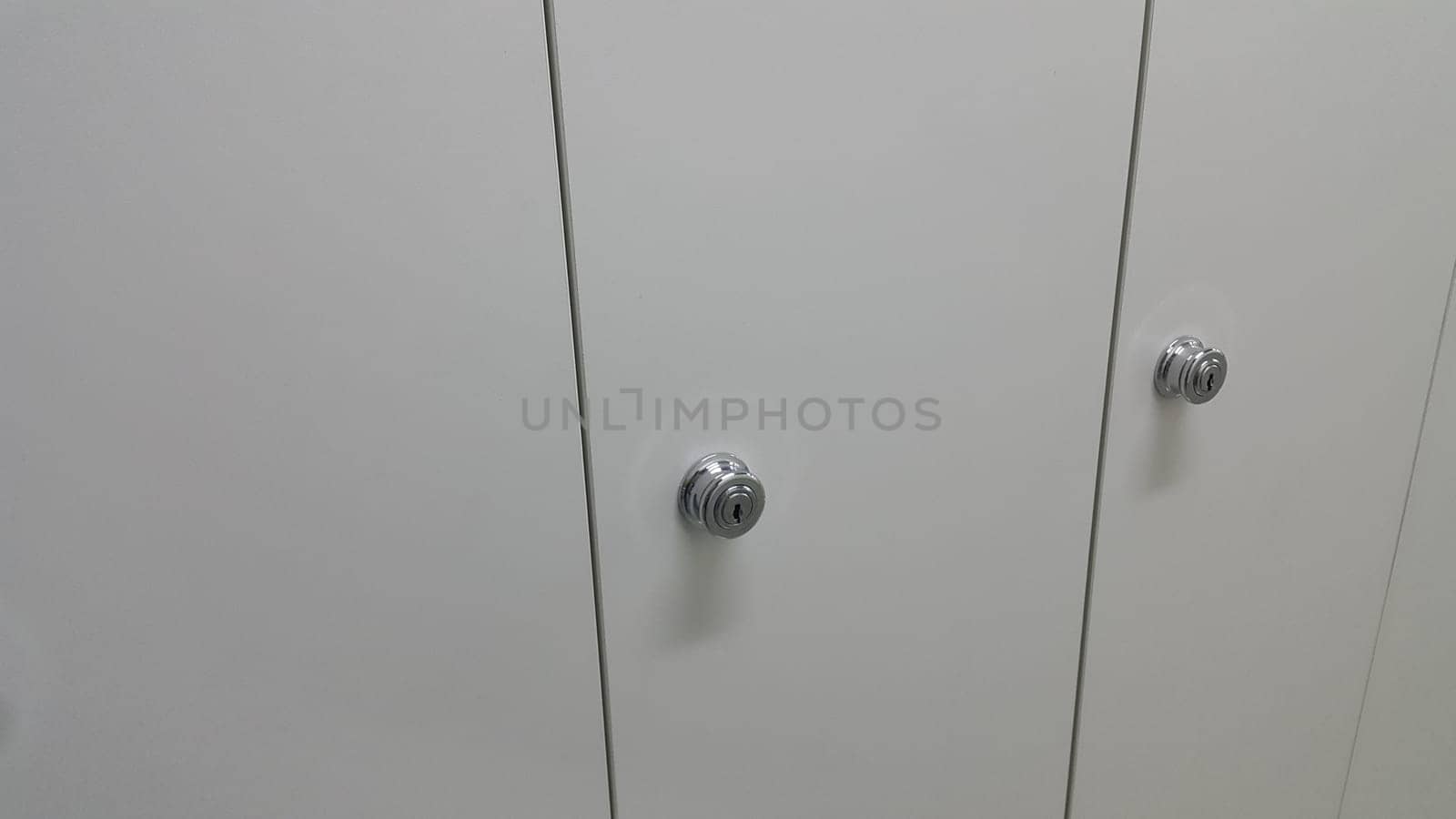 Perspective view of lockers or cupboards in a row with white doors, keys and locks