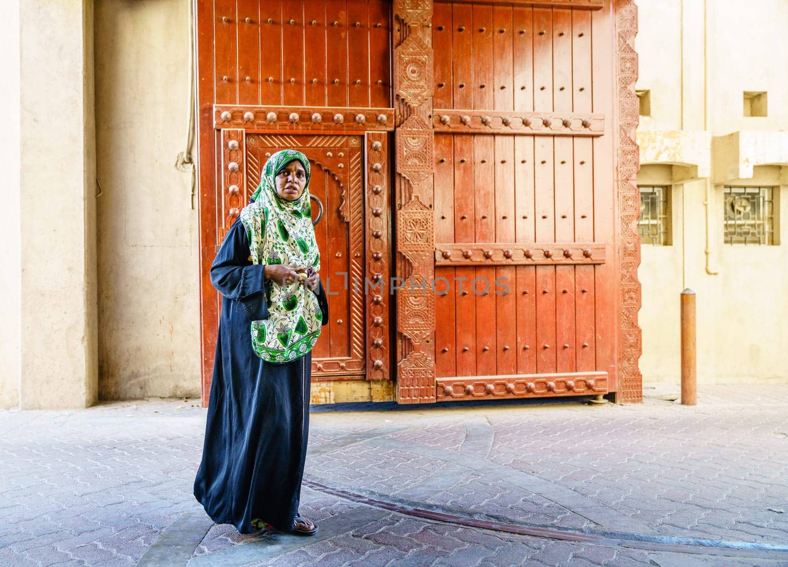 Nizwa, Oman, December 2, 2016: Middle-aged local woman is walking through the town gates at Friday Market in Nizwa, Oman
