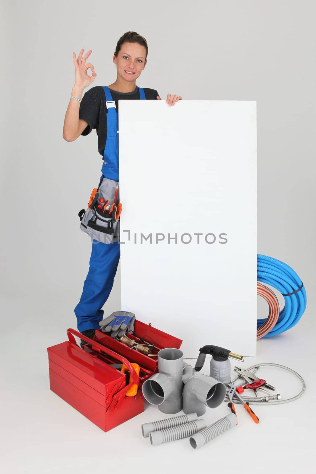 Female plumber with tools of the trade and a board left blank for your message