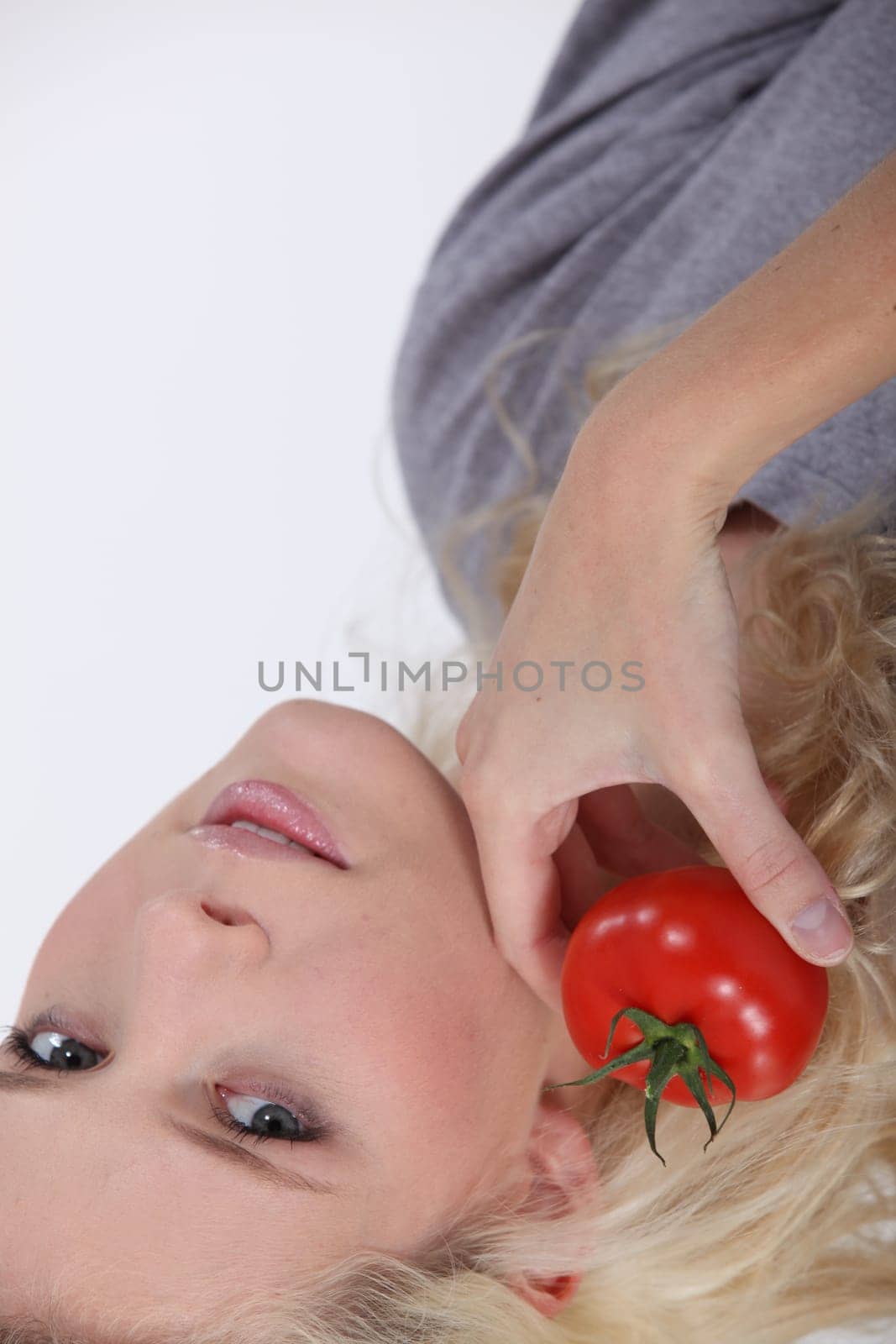blonde woman posing with a tomato