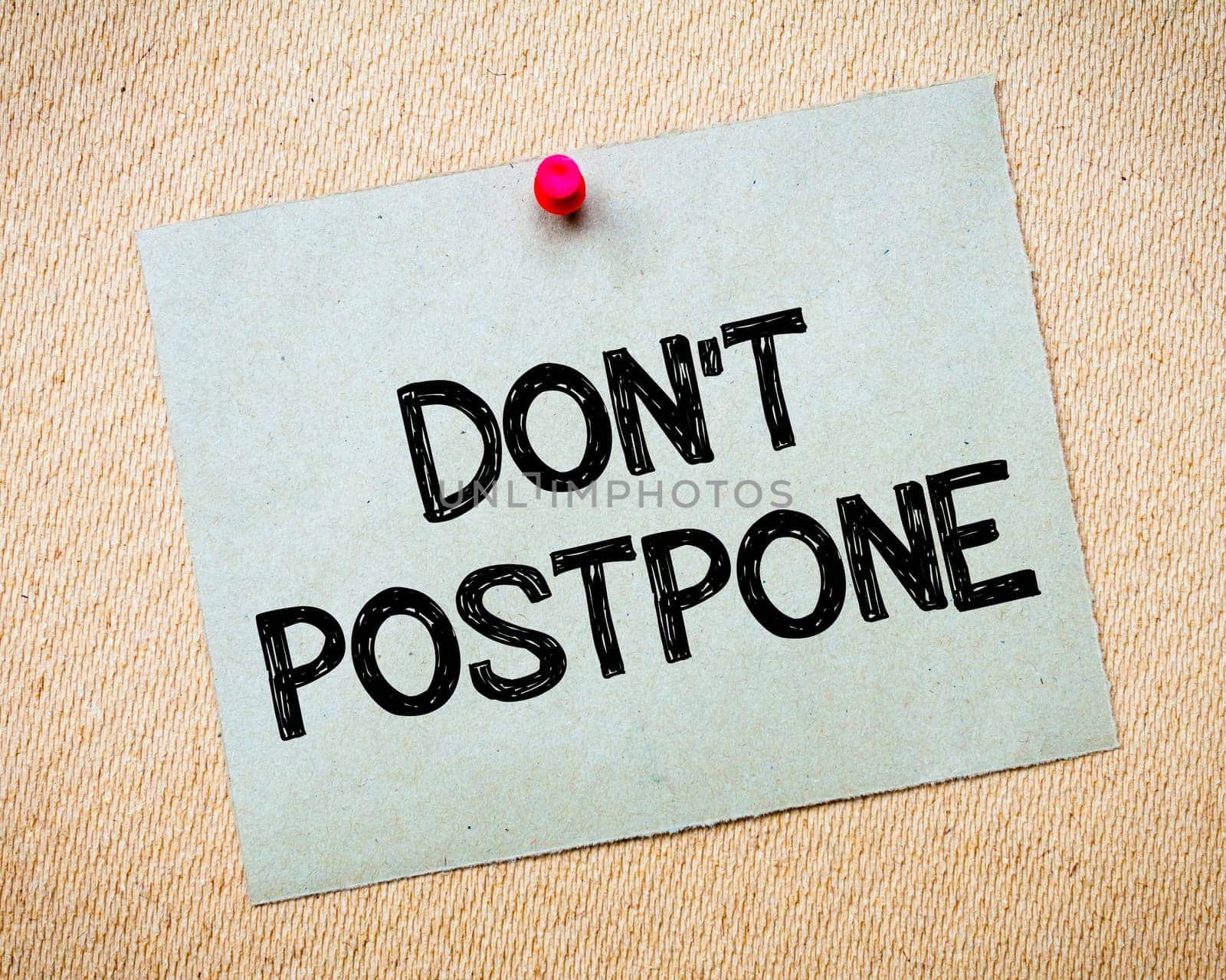 Recycled paper note pinned on cork board.Don' t Postpone Message. Motivational Concept Image