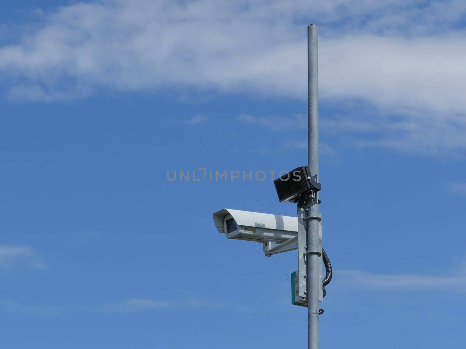 Surveillance camera on a pole high in the blue sky