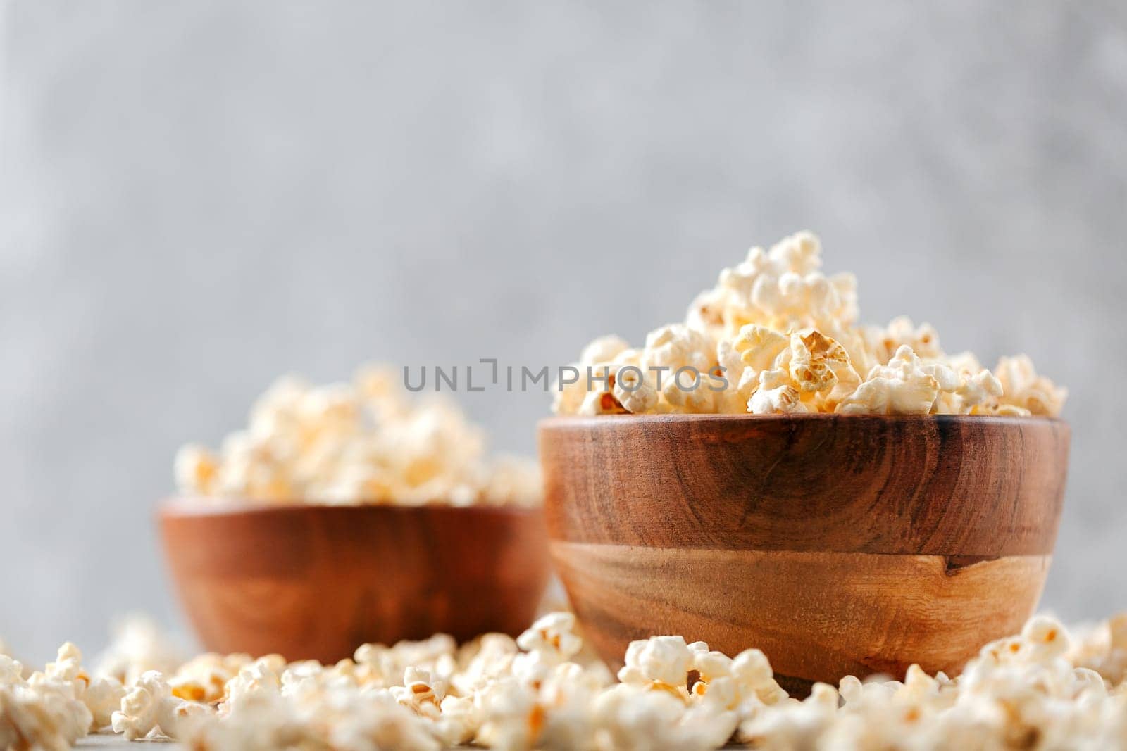 Two wooden bowls of salted popcorn on rustic grey table. Selective focus and copyspace for text. Concept of relax and time off.