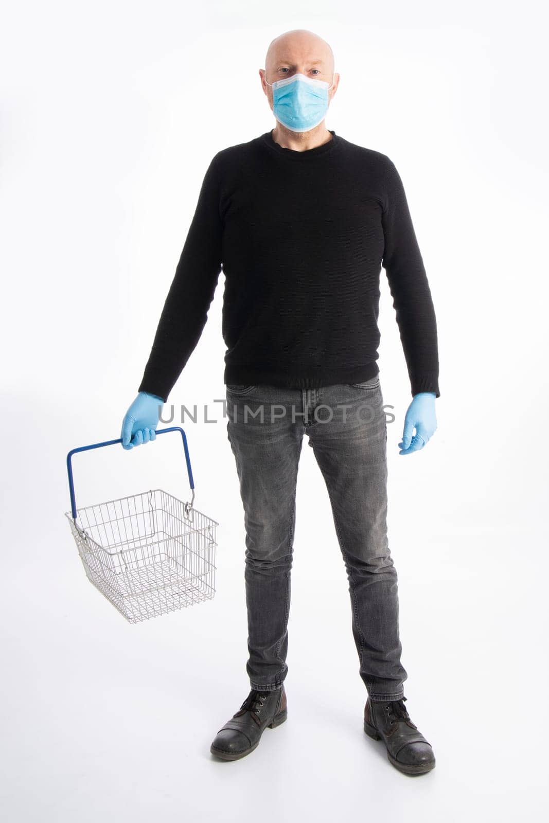 Man with mouth protection and hand gloves carrying a shopping basket, isolated on white background