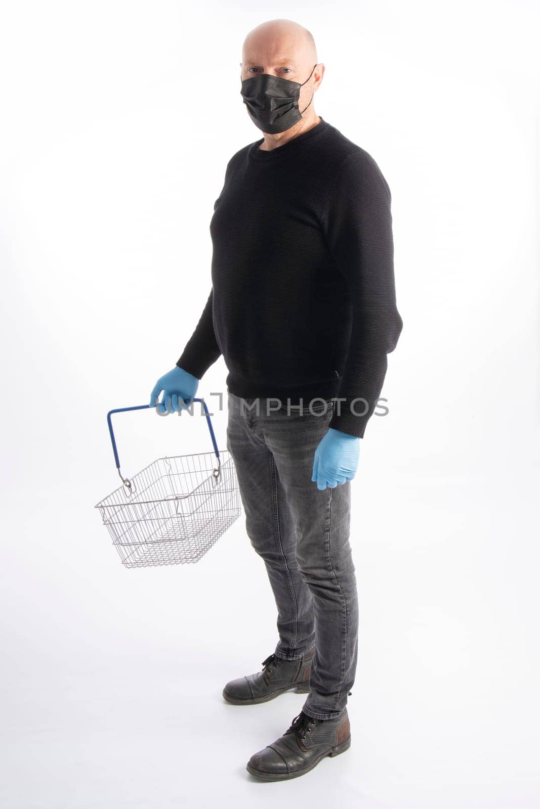 Man with mouth protection and hand gloves carrying a shopping basket, isolated on white background