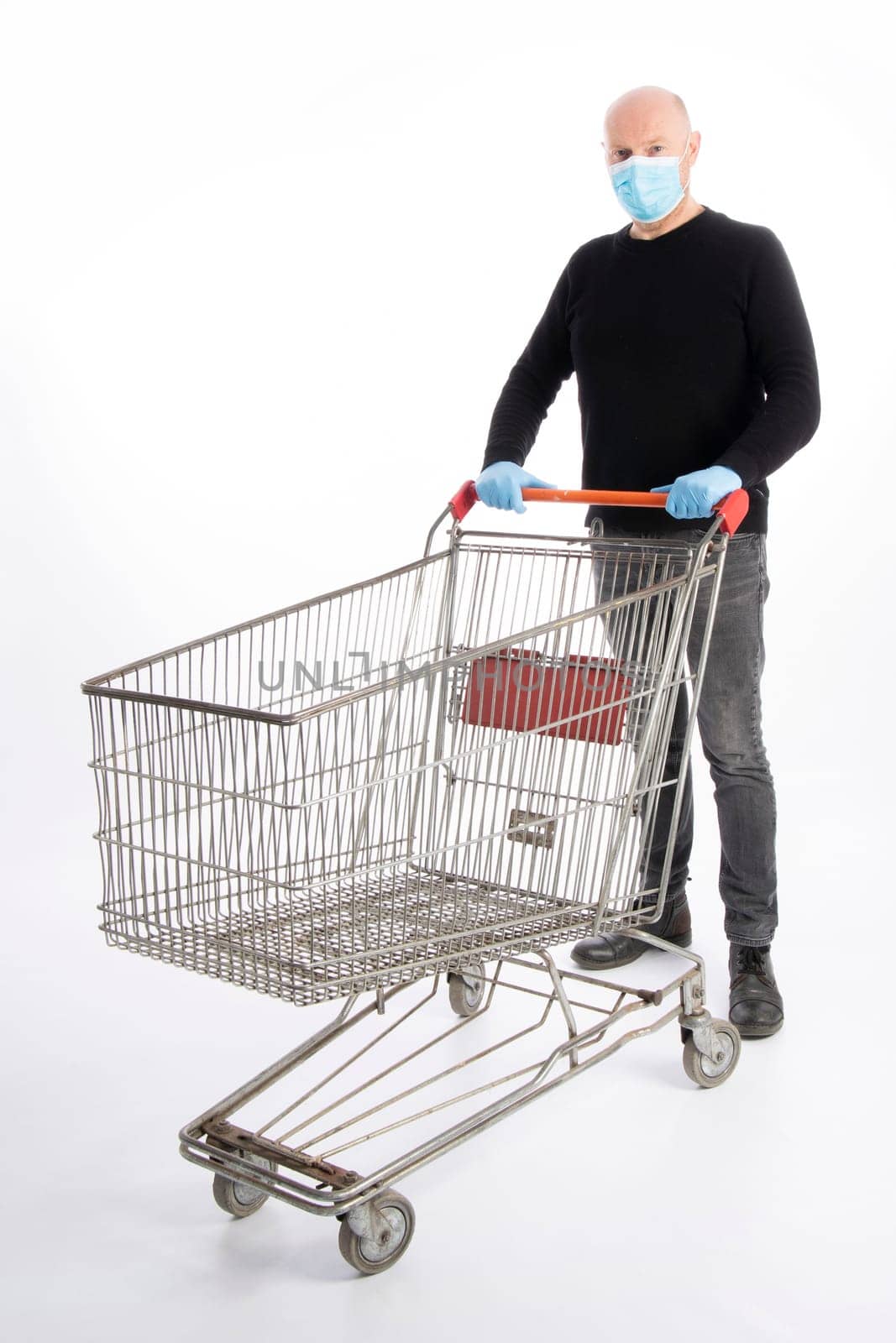 Man with mouth protection and hand gloves pushing a shopping cart, isolated on white background