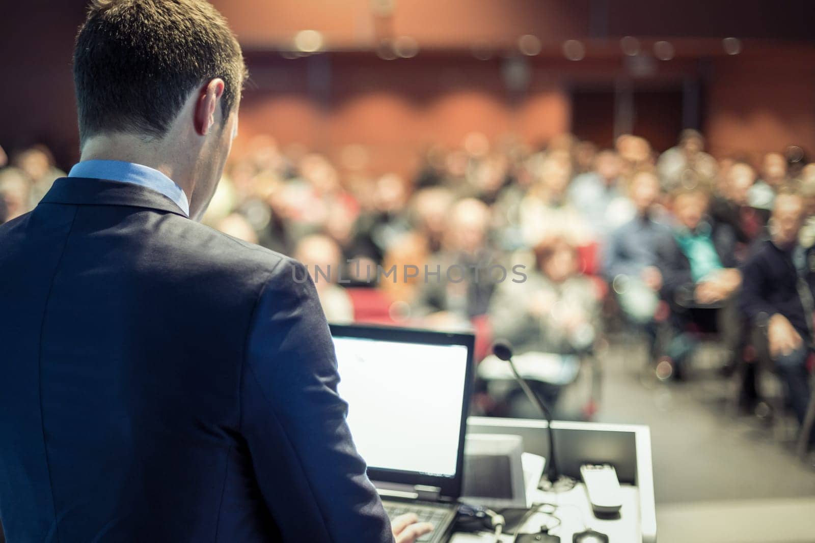 Speaker at Business Conference with Public Presentations. Audience at the conference hall. Entrepreneurship club. Rear view. Panoramic composition. Background blur.