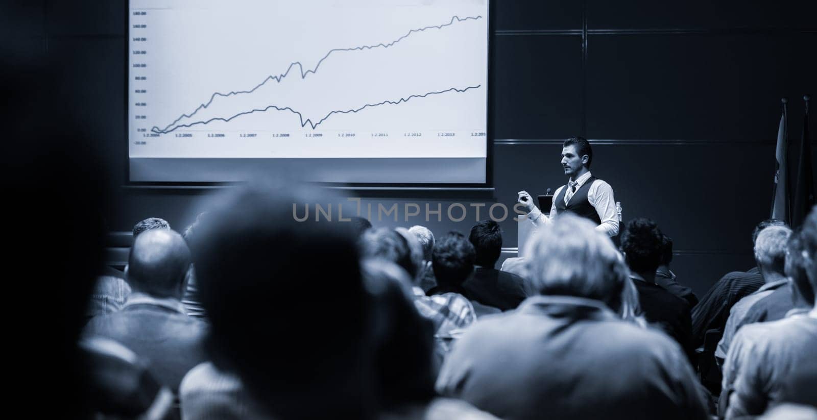Speaker Giving a Talk at Business Meeting. Audience in the conference hall. Business and Entrepreneurship concept. Black and white blue toned image.
