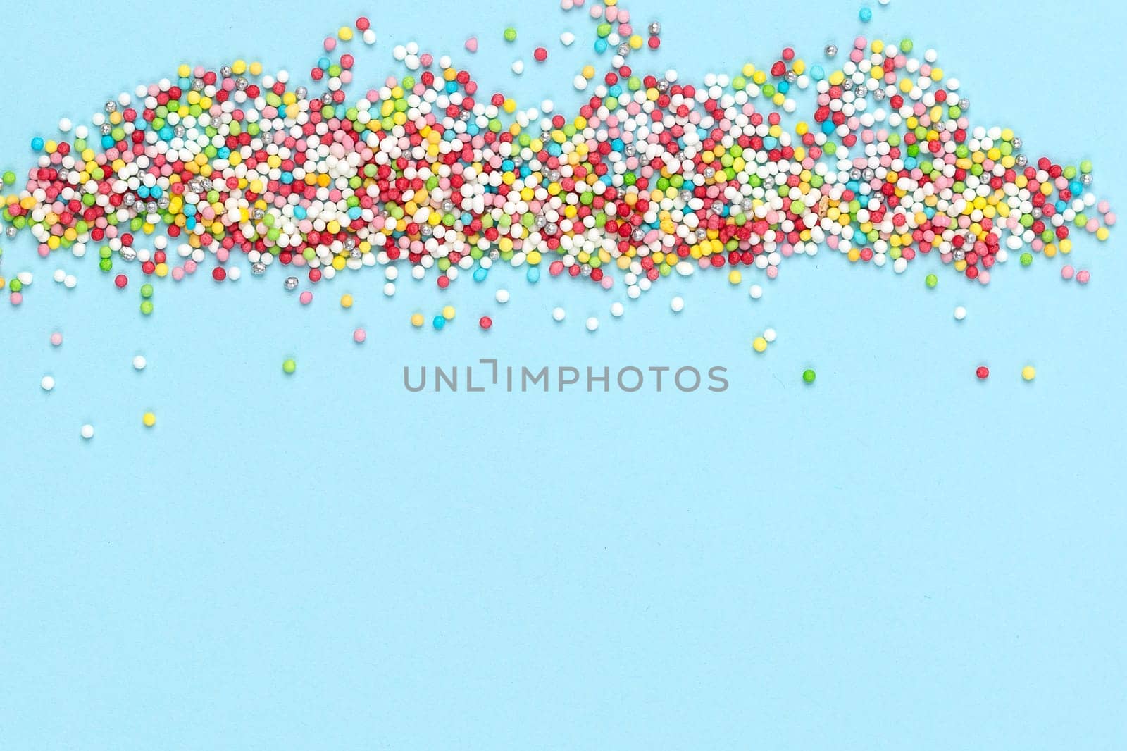 Multicolored candies for sweets on light blue background. Flat lay, copyspace, top view. Food concept. Banner.