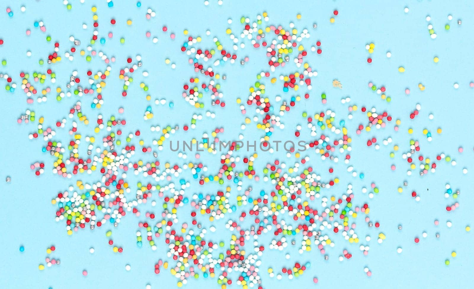Multicolored candies for sweets on light blue background. Flat lay, copyspace, top view. Food concept. Banner.
