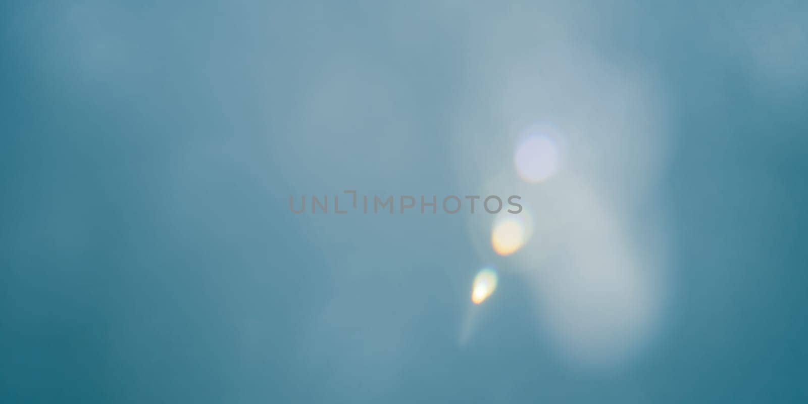 Abstract blue bokeh background with real lens flare