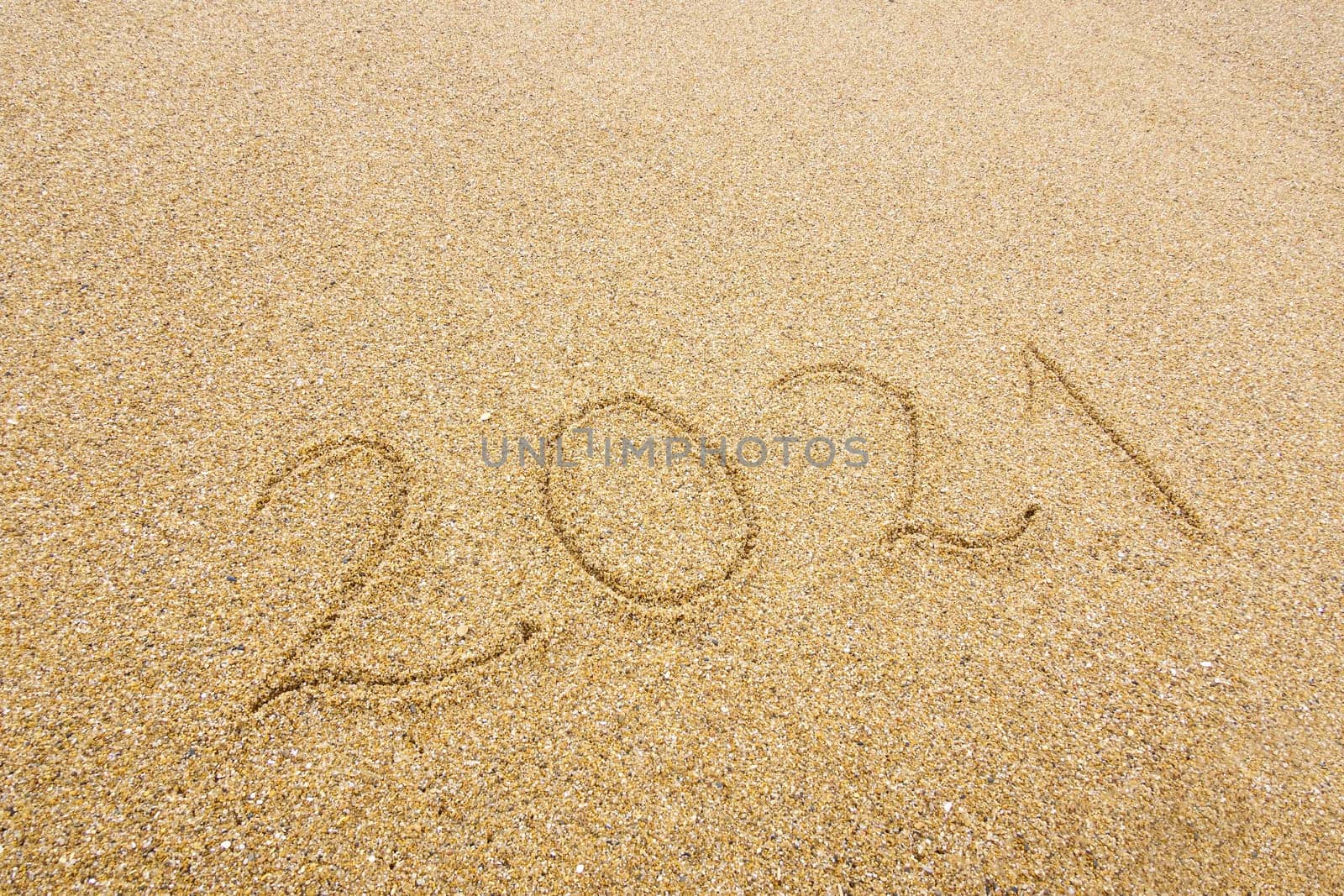 2021 handwritten on beach sand, new year and holiday concept