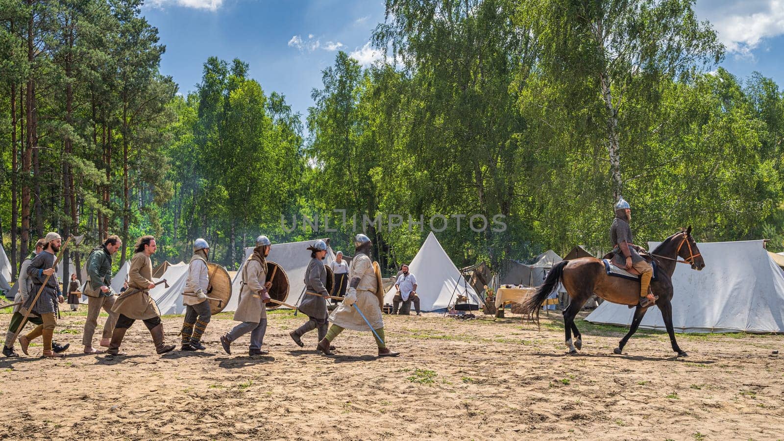 Cedynia, Poland, June 2019 Chieftain on the horse and his warriors passing tent camp. Historical reenactment of Battle of Cedynia between Poland and Germany, circa 11th century