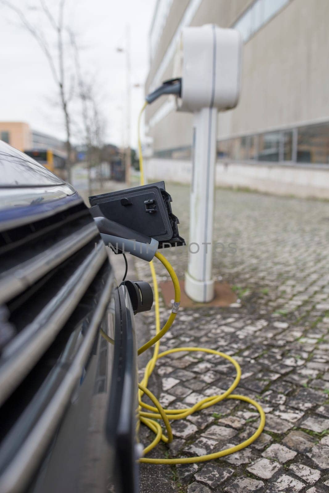 Petrol-electric hybrid car charging at urban charging station. Selective focus