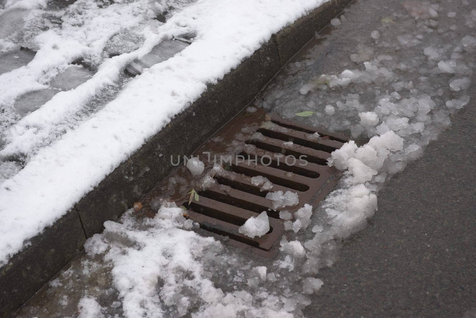 4 - Highway kerbside storm drain covered in melting snow. Winter seasonal weather in the month of december in the UK. Showing urban water management
