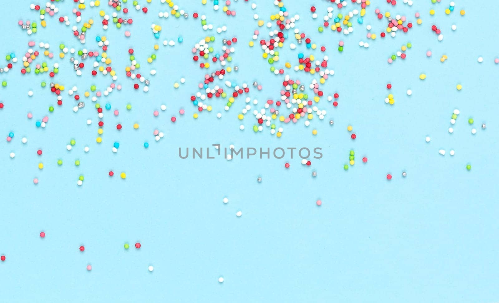 Multicolored candies for sweets on light blue background. Flat lay, copyspace, top view. Food concept. Banner.