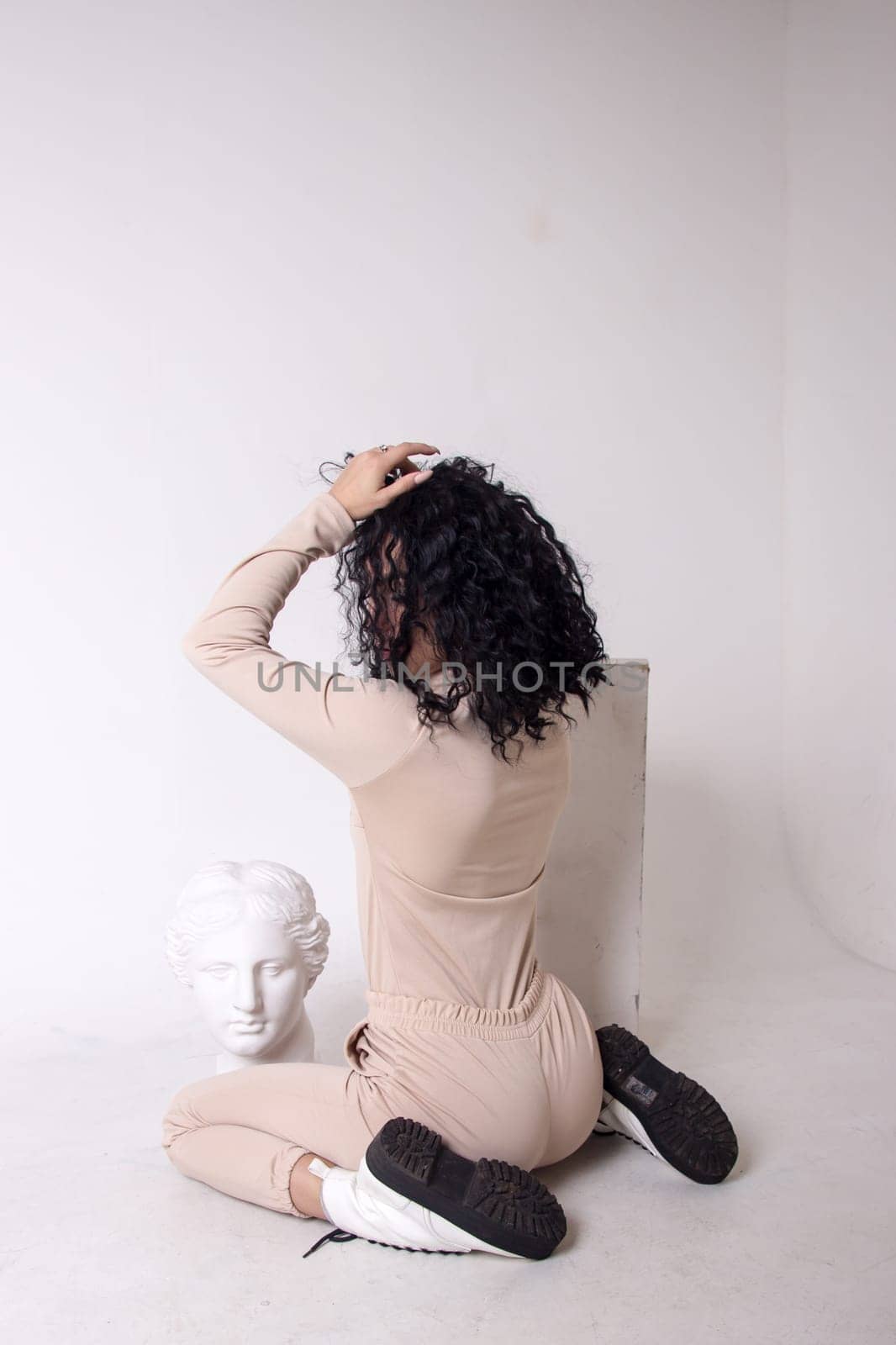Fitness woman poses sitting, showing buttocks.