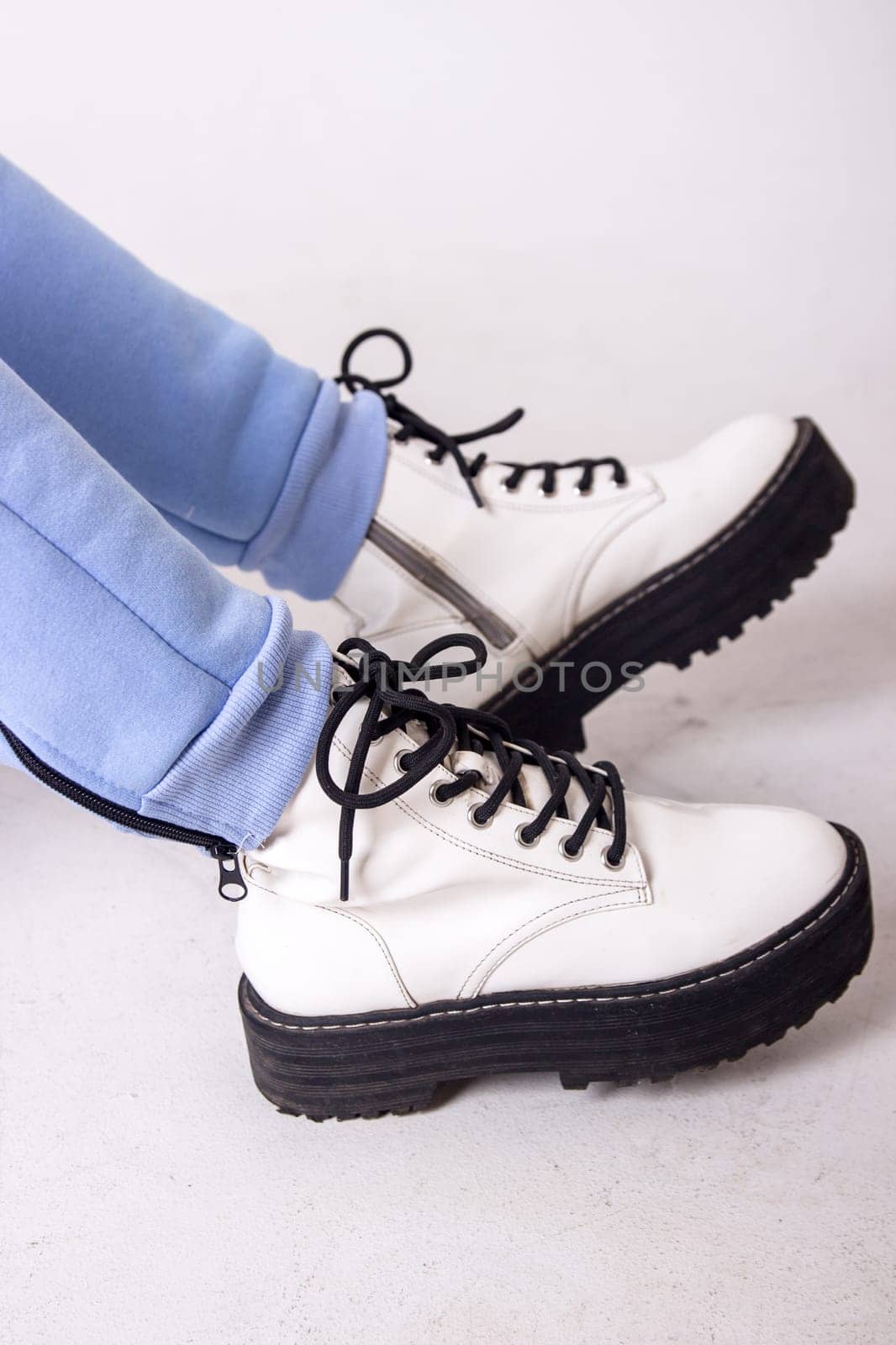 Female sneakers. White female shoes on feet.