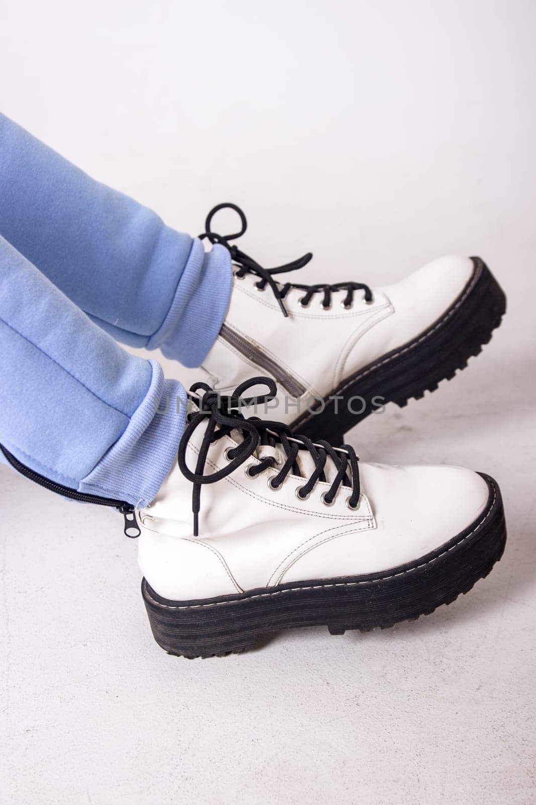 Female sneakers. White female shoes on feet.