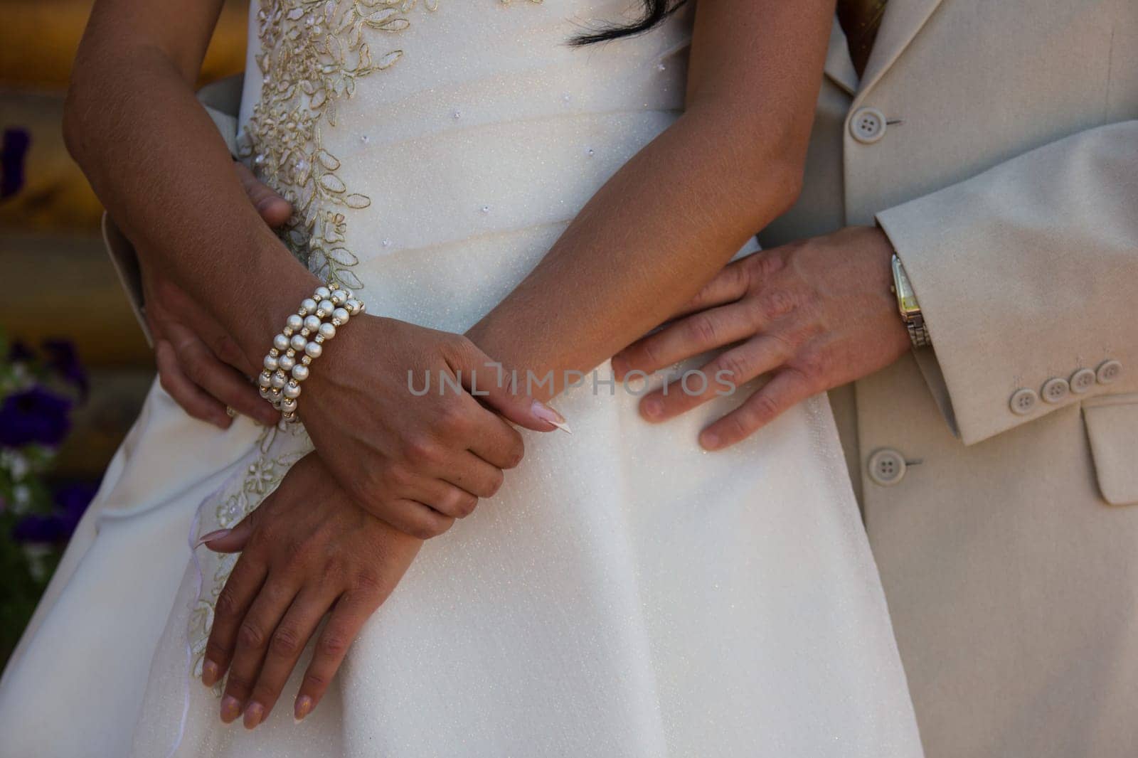 the groom puts his arm around the bride's waist, the bride keeps her arms crossed.