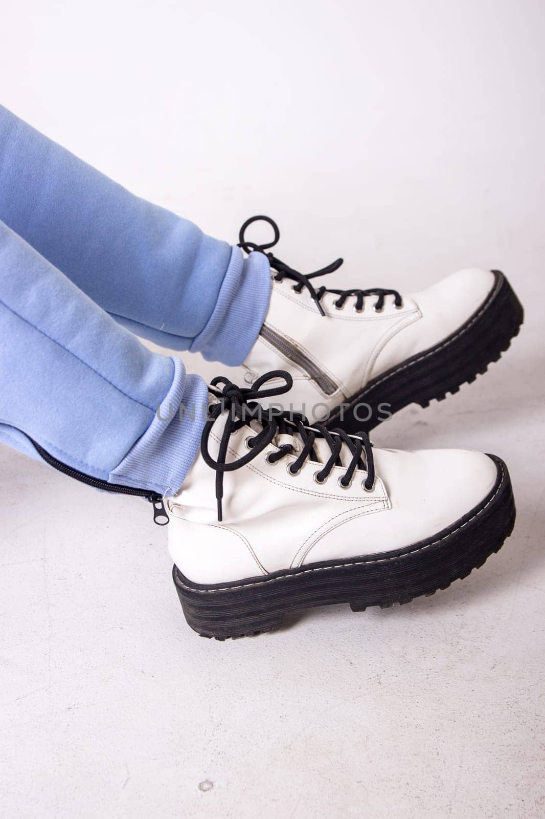 Female sneakers. White female shoes on feet.