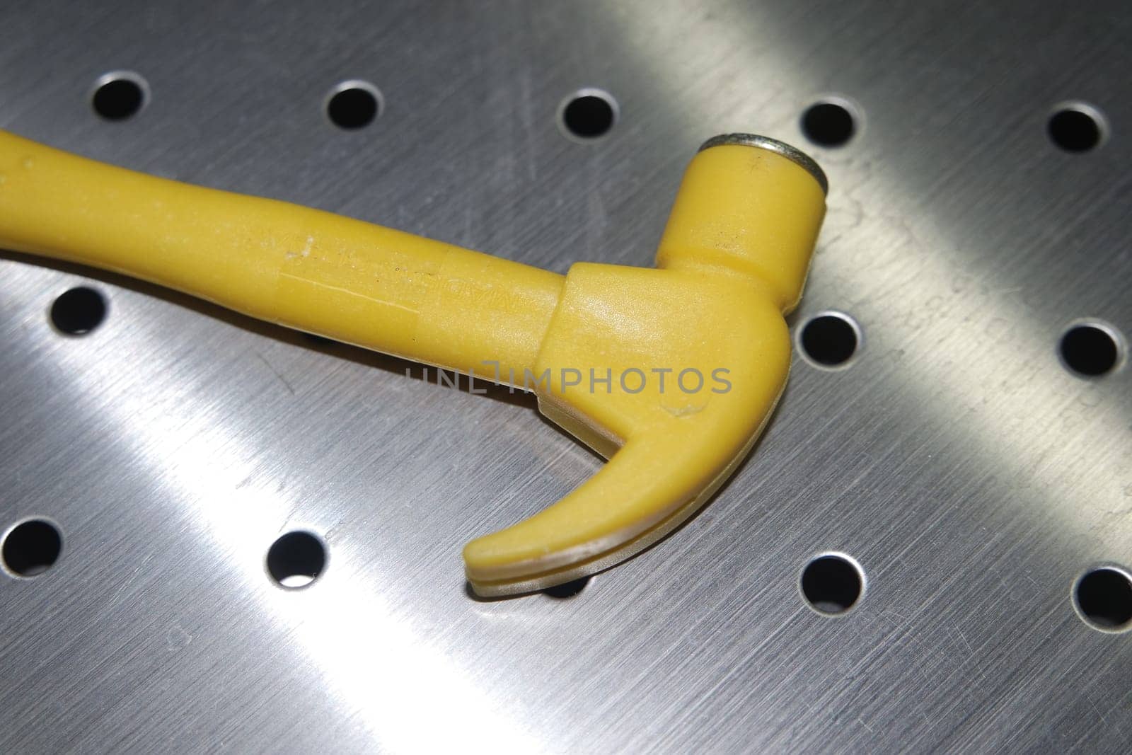 Selective focused, closeup view of toy hammer made from plastic placed on metal background