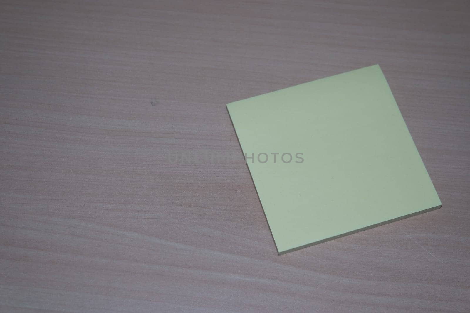 Close-up, selective focus: Yellow sticky note paper placed on a wooden table with copy space for text