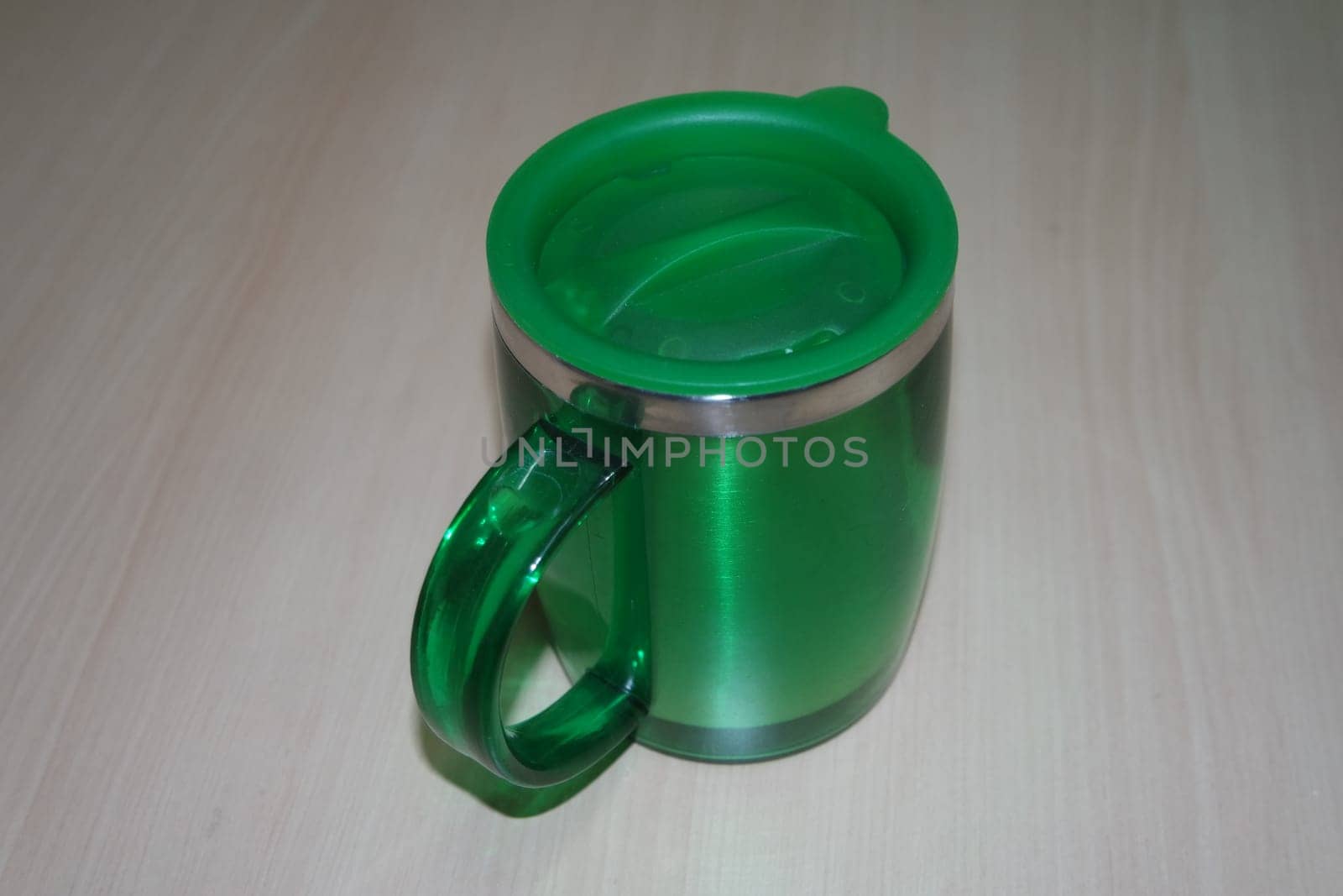 Beautiful coffee green hot mug with green led, placed over white floor. Closeup perspective view of a mug on white desk.