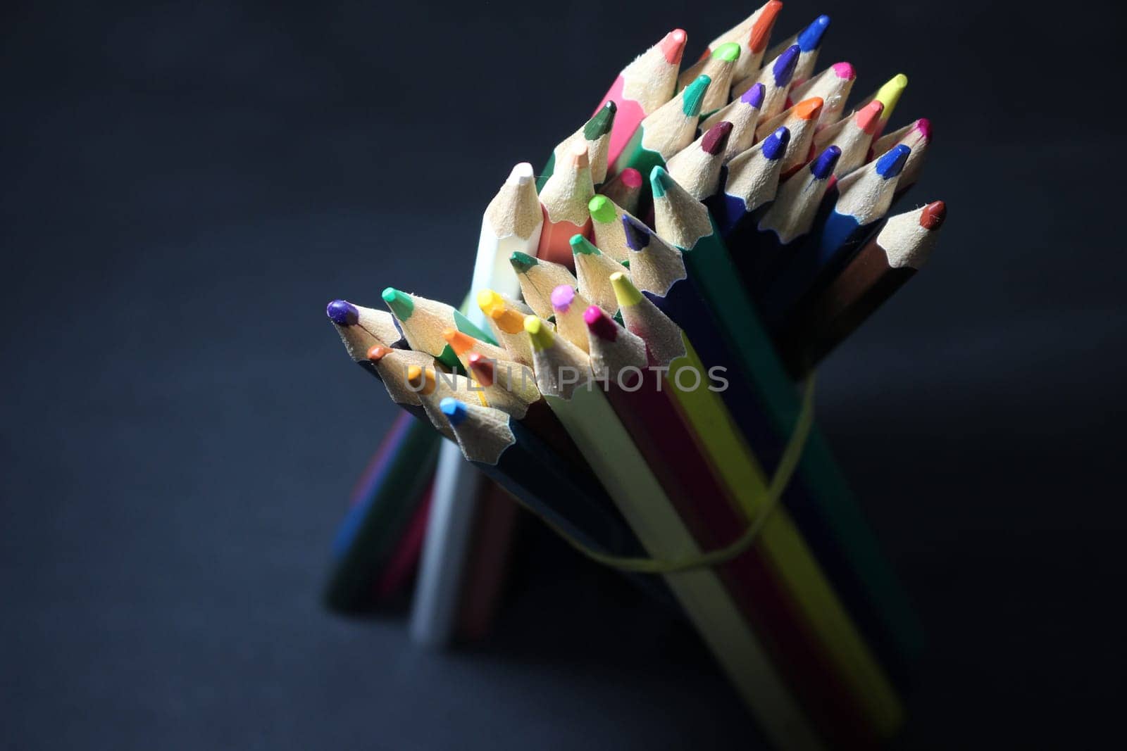 Close-up view of bright colored multicolor pencils on black background