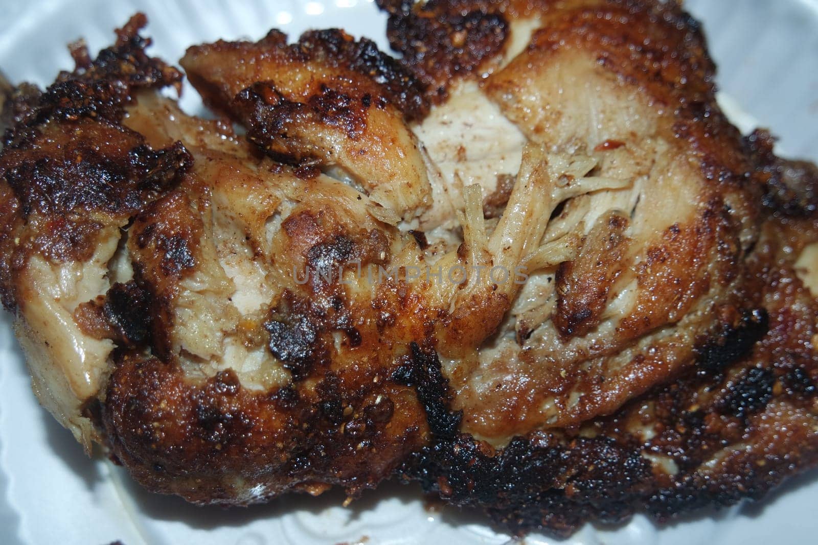 Close up of roasted chicken pieces in a white plate served for meal. Meat background for restaurant advertisements