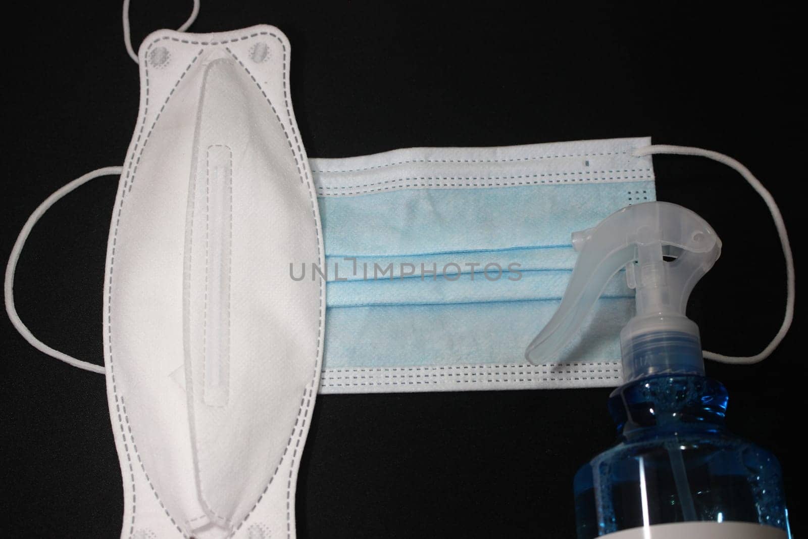 blue color cloth face mask with hand sanitizer bottle isolated on black background