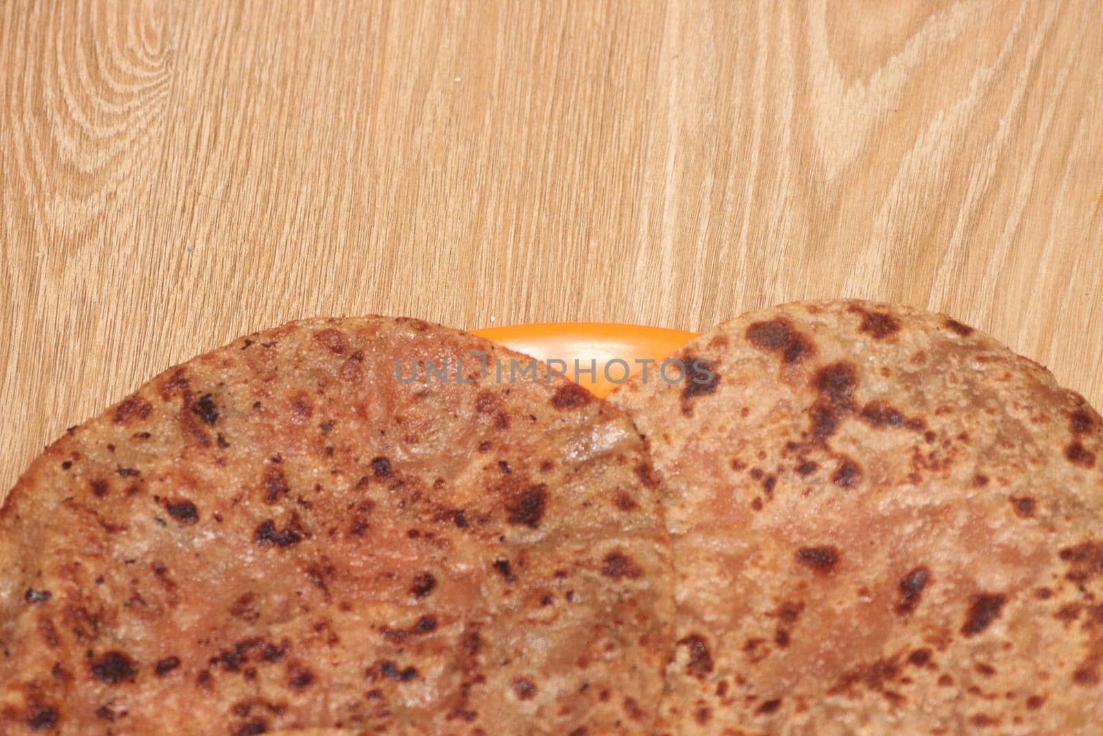 Traditional paratha - Macro closeup with selective focus of homemade oily bread or parotta on a plate on wooden floor. Chapati is traditional food of southeast Asia.