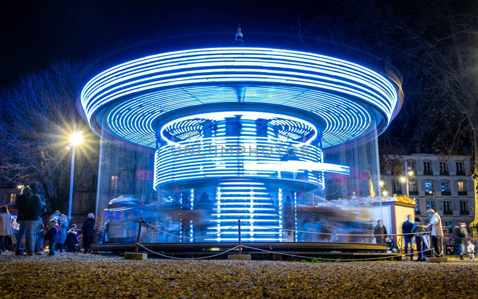 BAYONNE, FRANCE - CIRCA DECEMBER 2020: Long exposure of carousel at night. Low angle shot with motion blur.