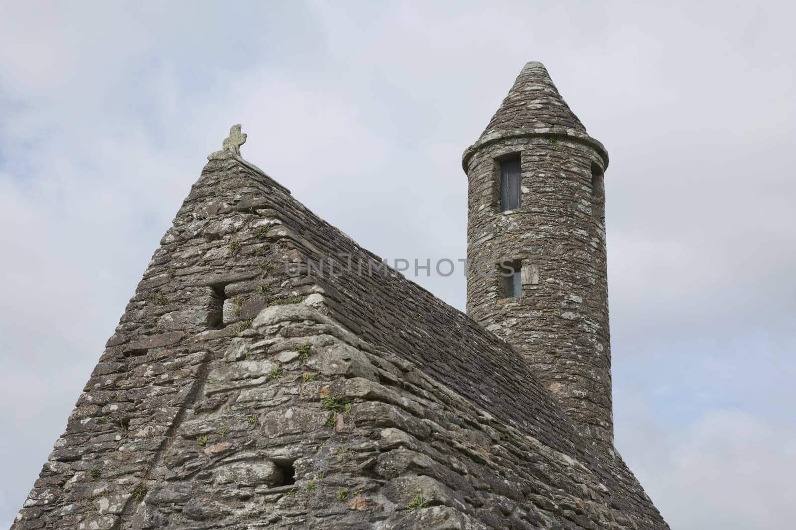 Glendalough, co. Wicklow, Ireland - August 10 2019 :Stone round tower and some ruins of a monastic settlement originally built in the 6th century in Glendalough valley, County Wicklow, Ireland.