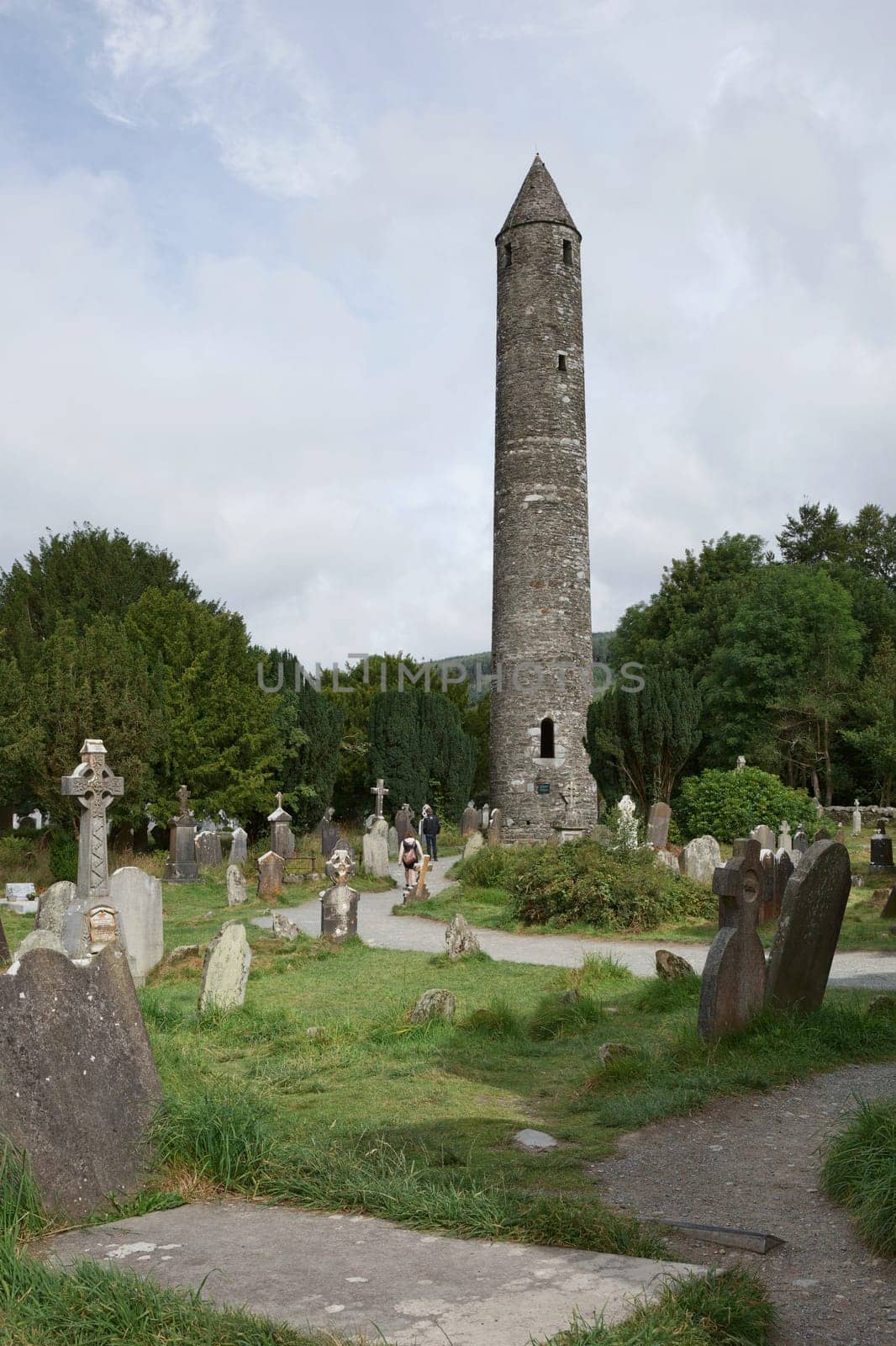 Glendalough, co. Wicklow, Ireland - August 10 2019 :Stone round tower and some ruins of a monastic settlement originally built in the 6th century in Glendalough valley, County Wicklow, Ireland.