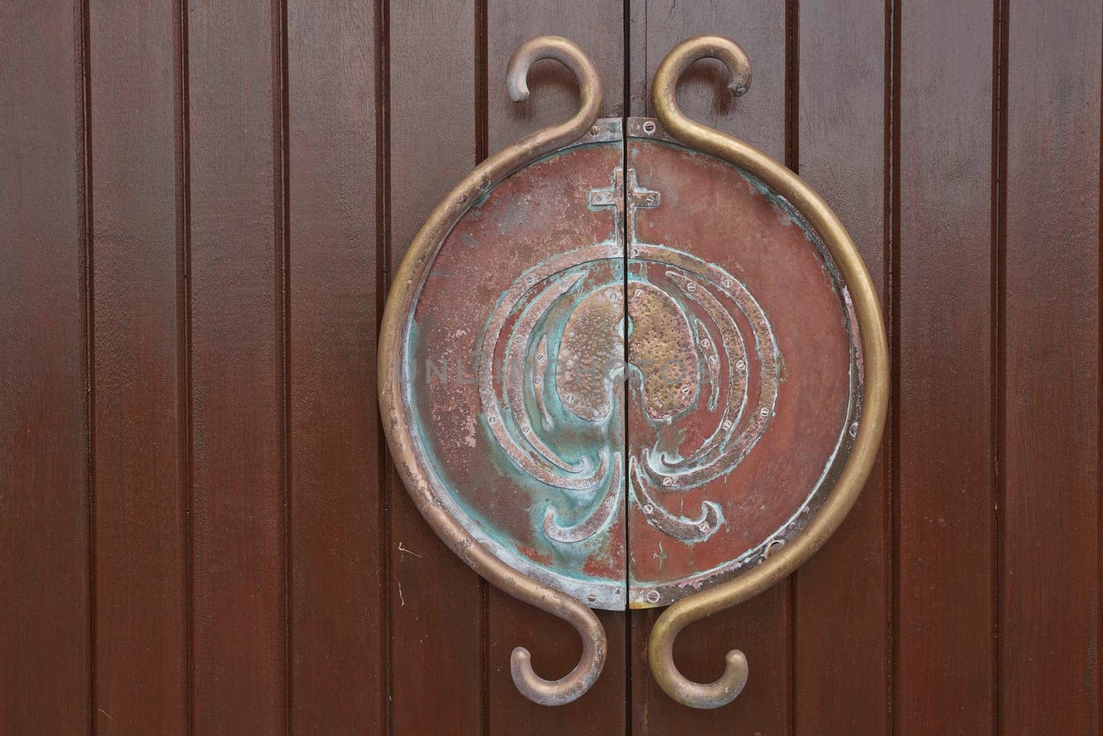 Medieval metal handle and doorknob on a wooden door.